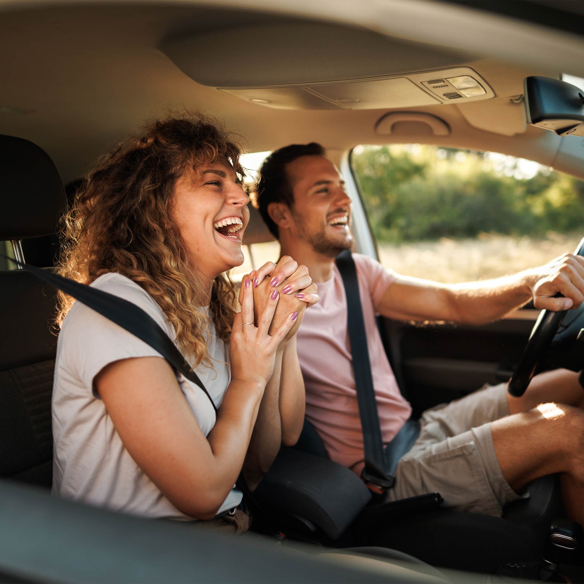 Two women smiling as they drive with the windows down.