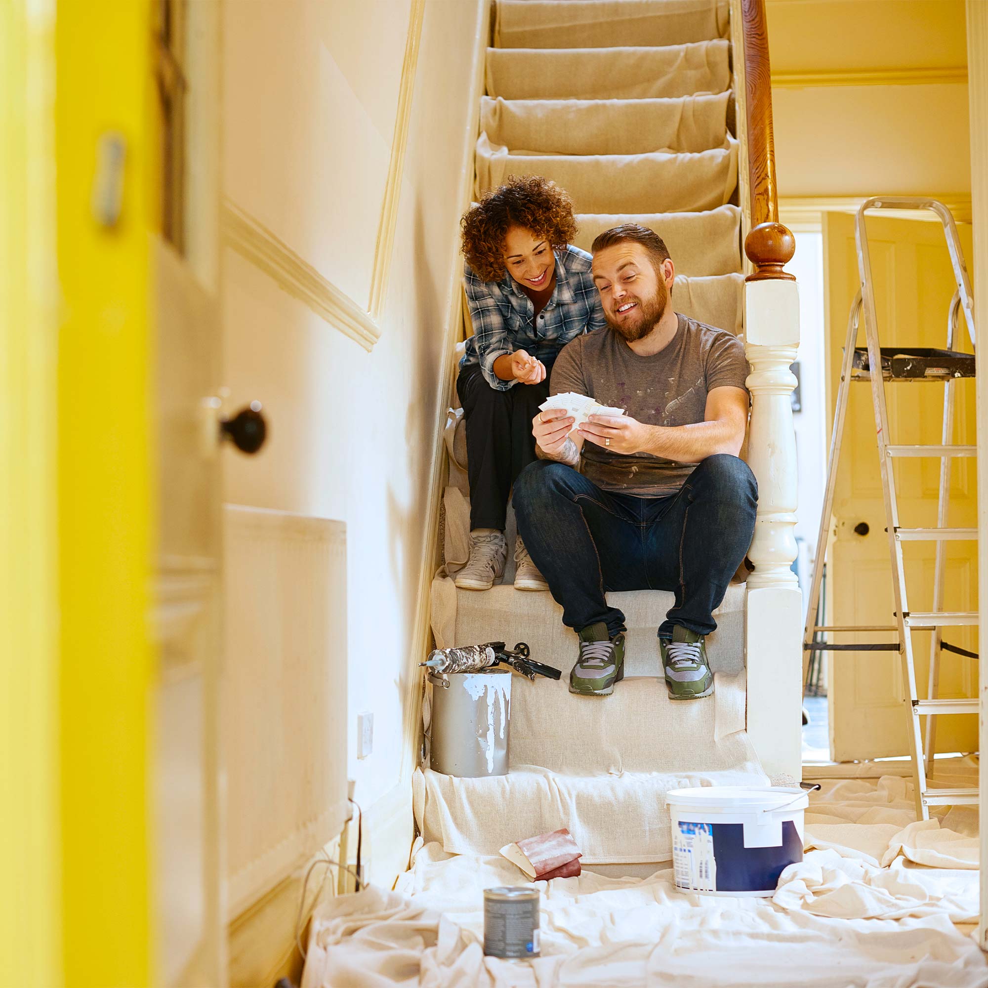 A man and woman sit on the stairs and take a break from painting.