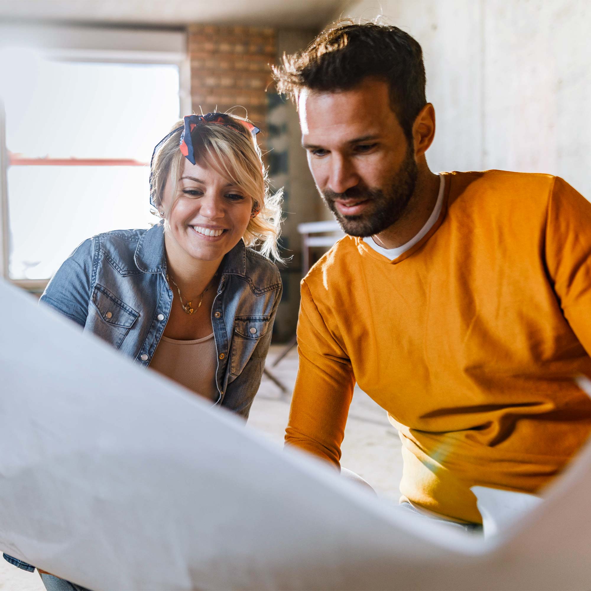 A man and woman look at their new house blueprint.