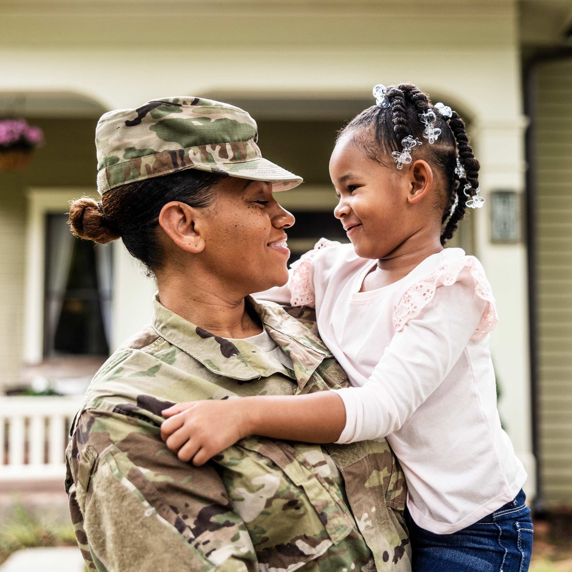 Military man and a woman both carry cardboard boxes into their new house.