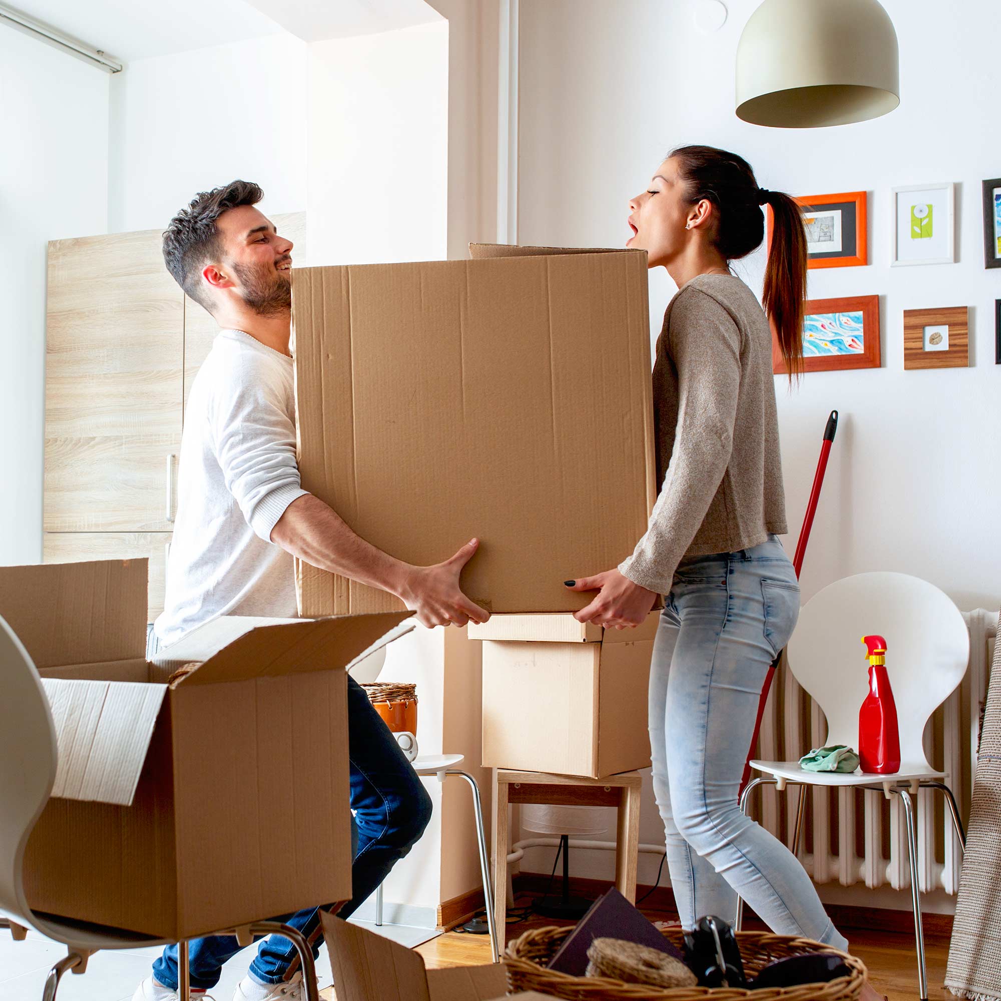 Two people carry a large cardboard box into a house together.