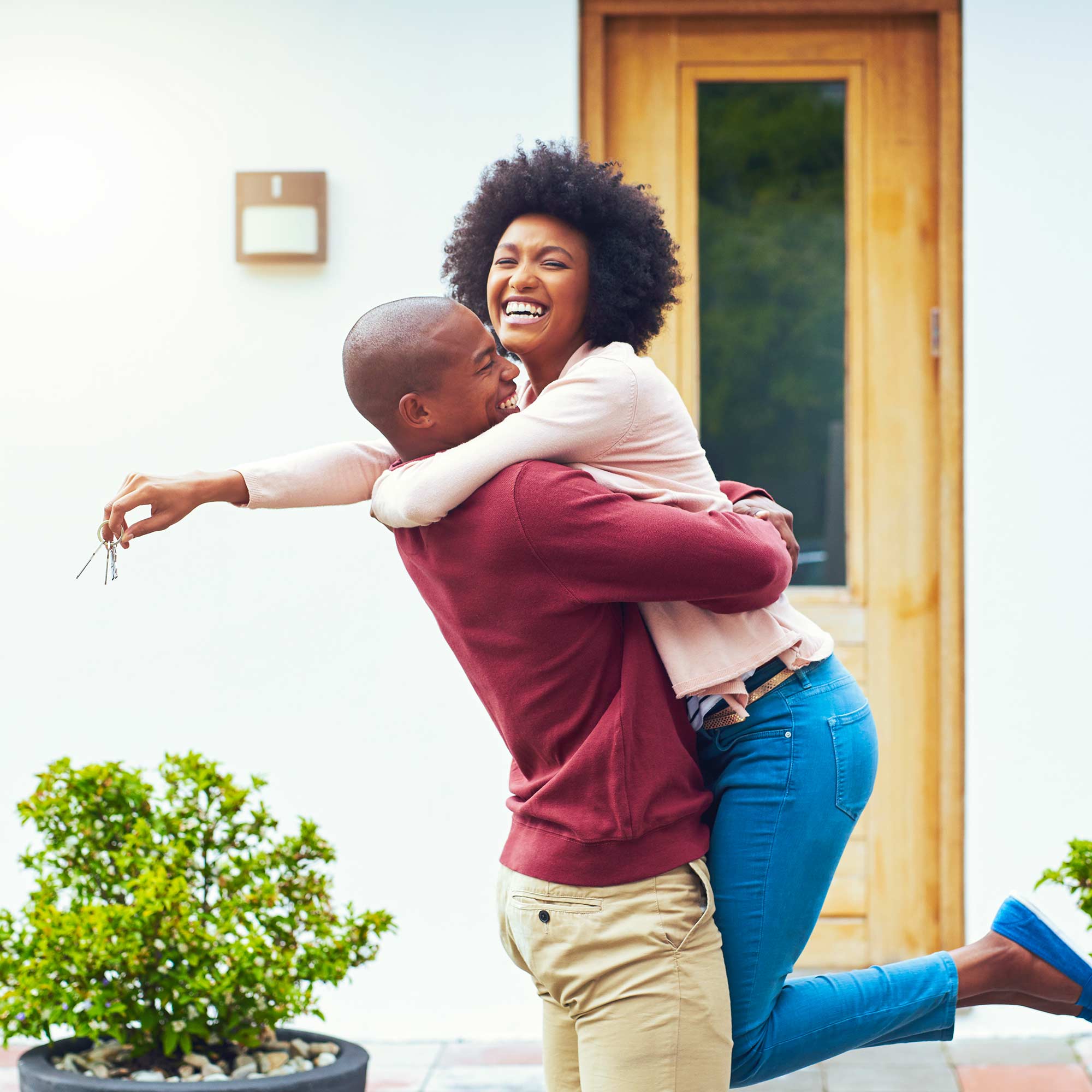 Woman jumps into her husband's arms and smiles.