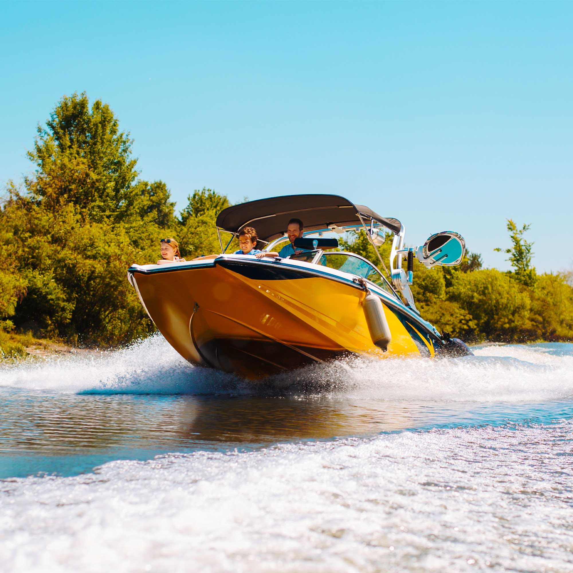 An orange boat speeds across the water on a sunny day.