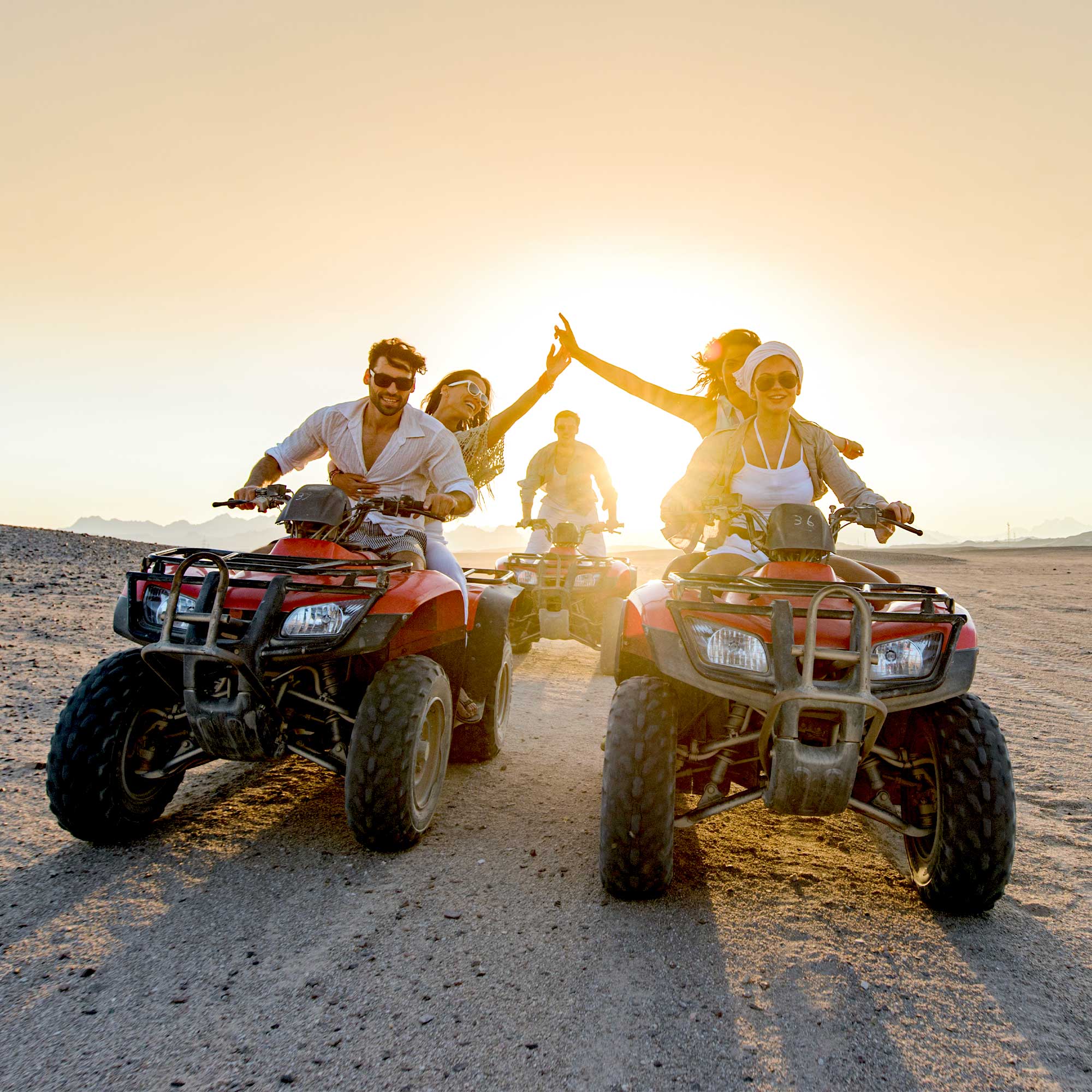Man, woman and friends riding four wheelers in the sand.
