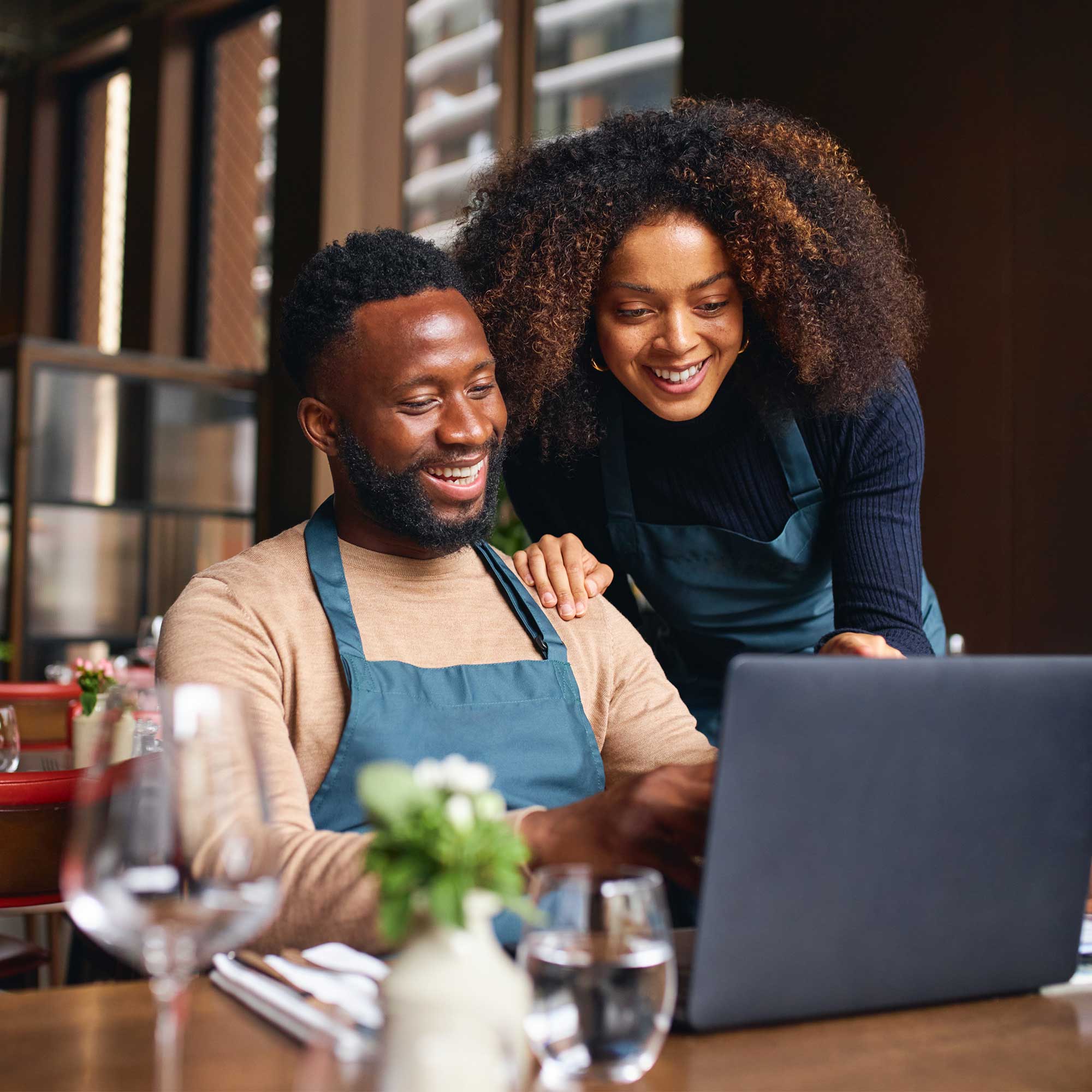 Woman in striped shirt and apron prints a receipt and smiles.