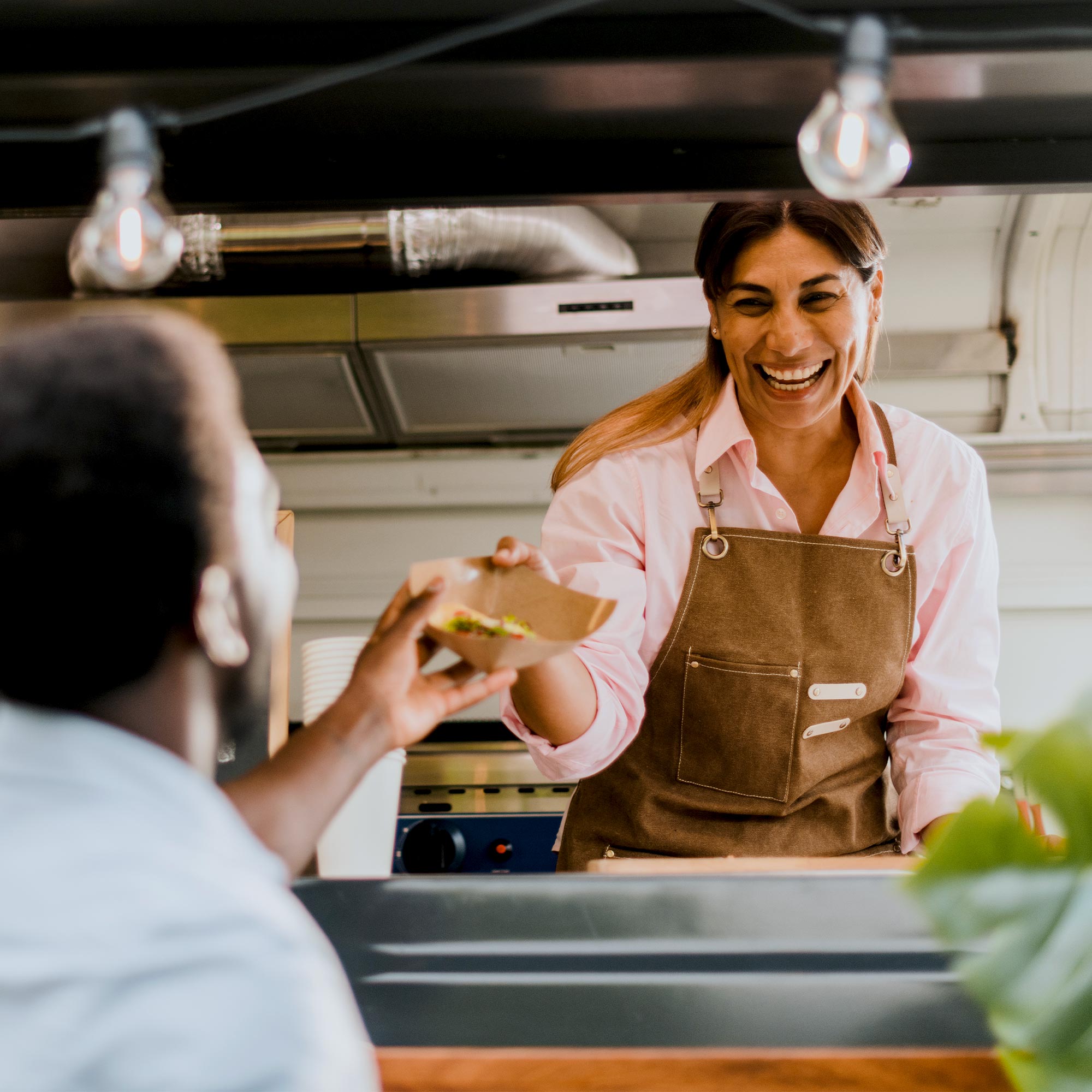 A woman wearing a blue shirt smiles as she pays with her debit card.