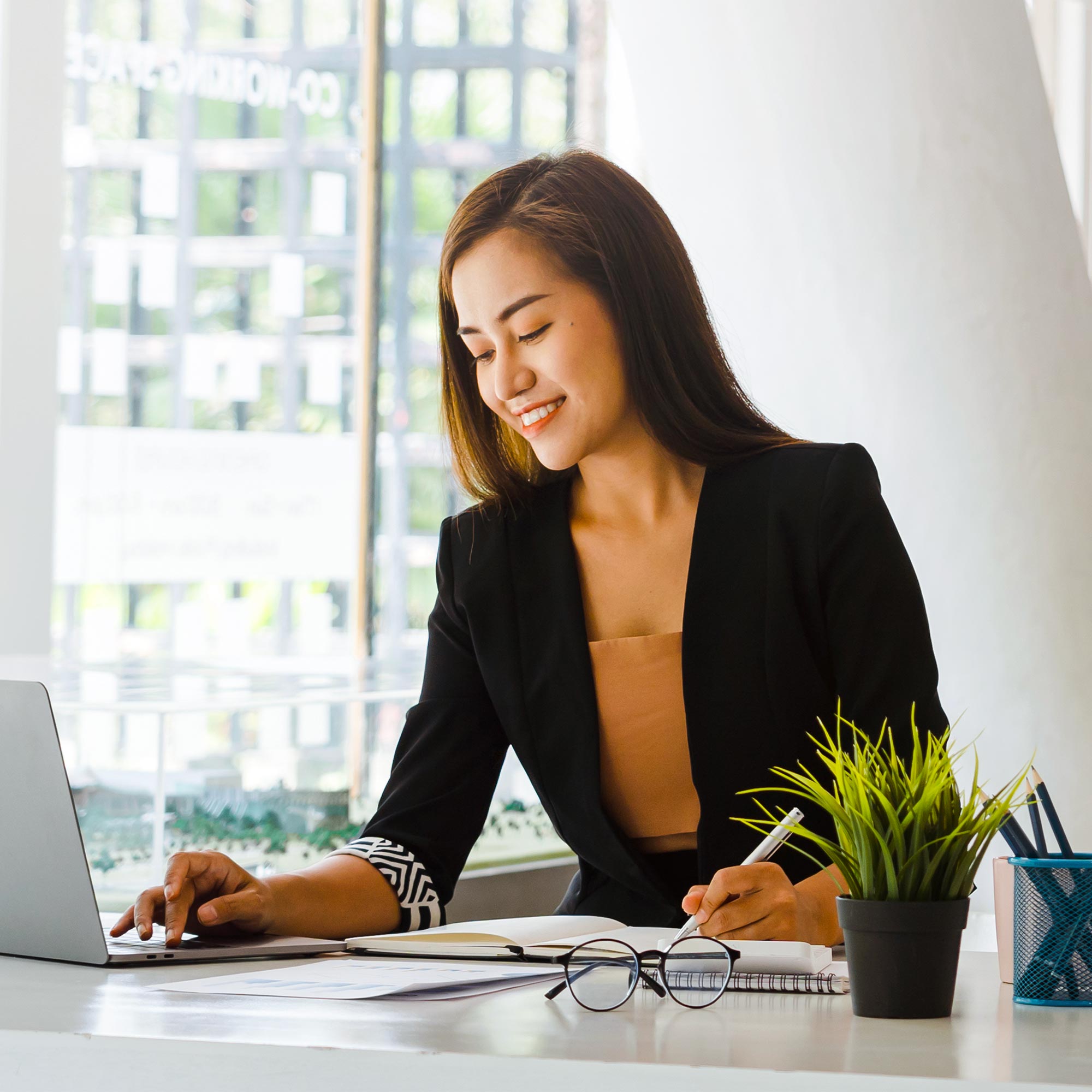 A woman smiles as she types at her desk workstation.