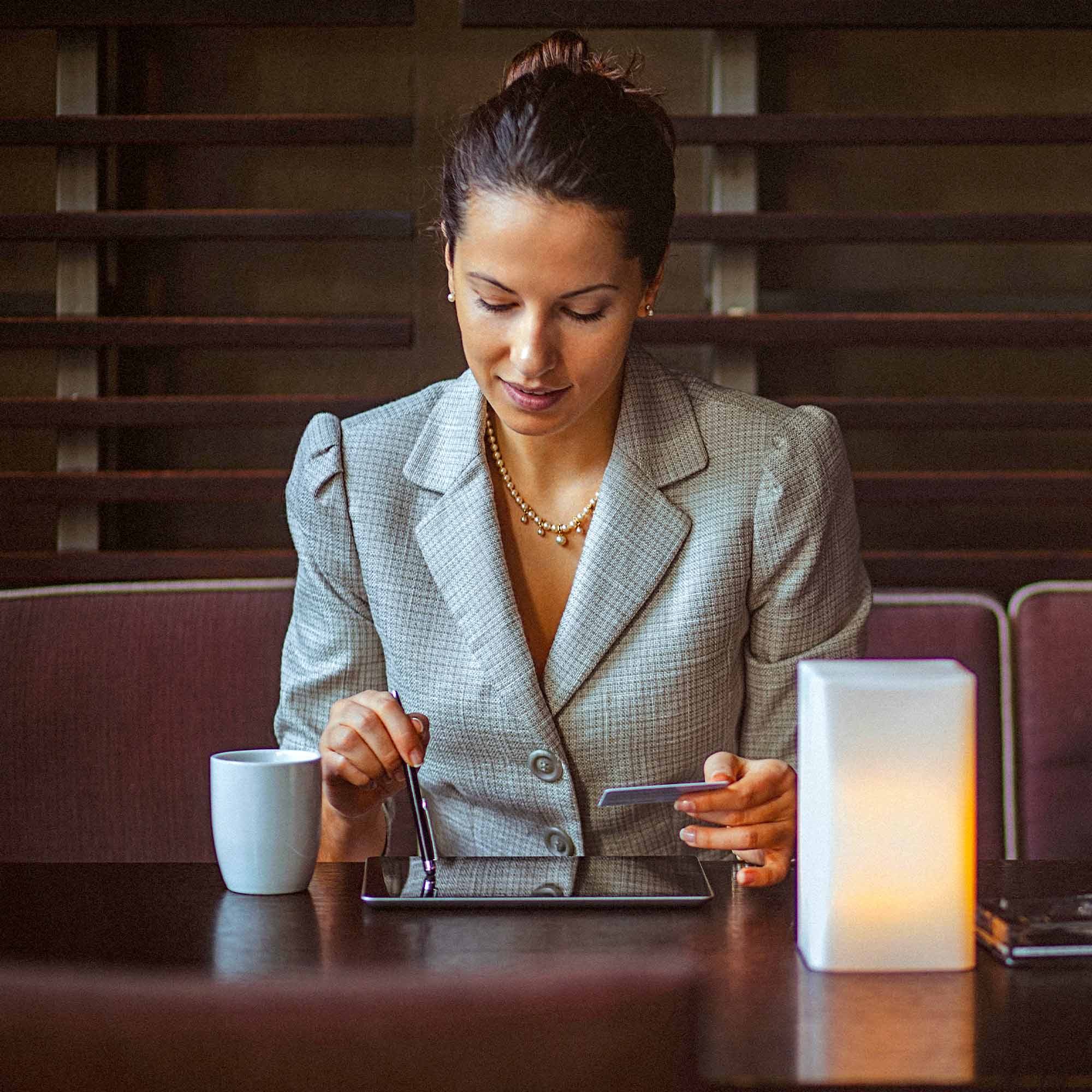 A man in a blue business suit, stands peering at his notebook.