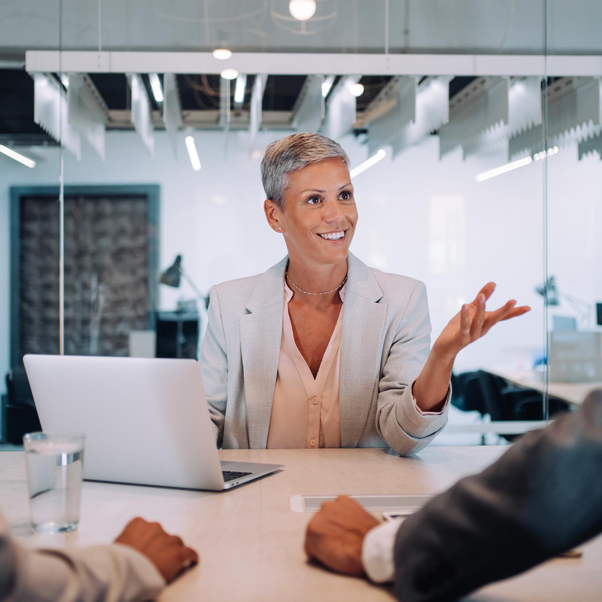A woman sitting at a desk leads a team meeting with two others.