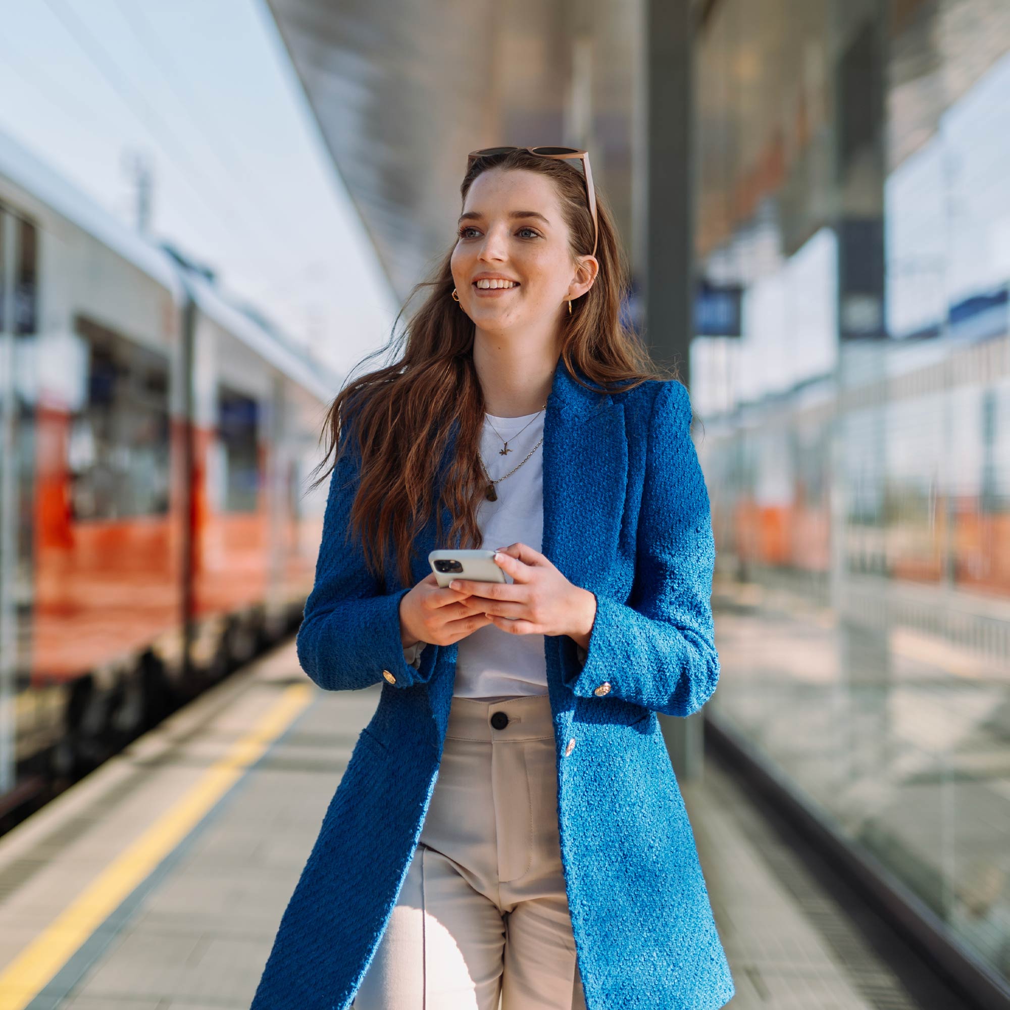 A woman stands and holds her notebook as she smiles at her cell phone.