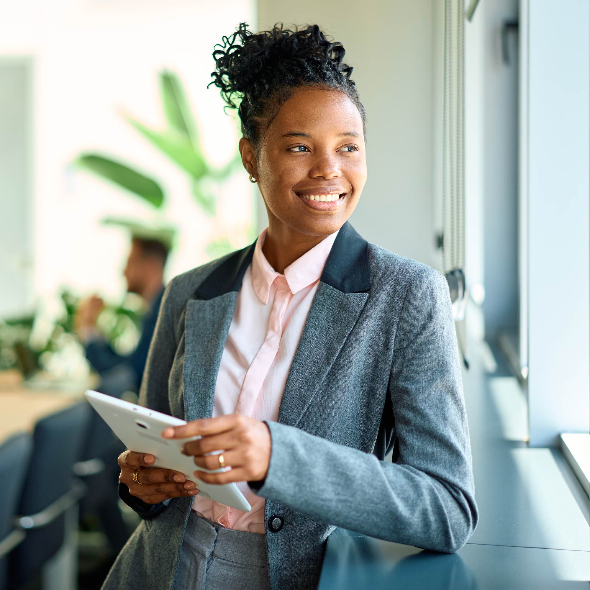 A woman in jeans sits casually and looks at her laptop.