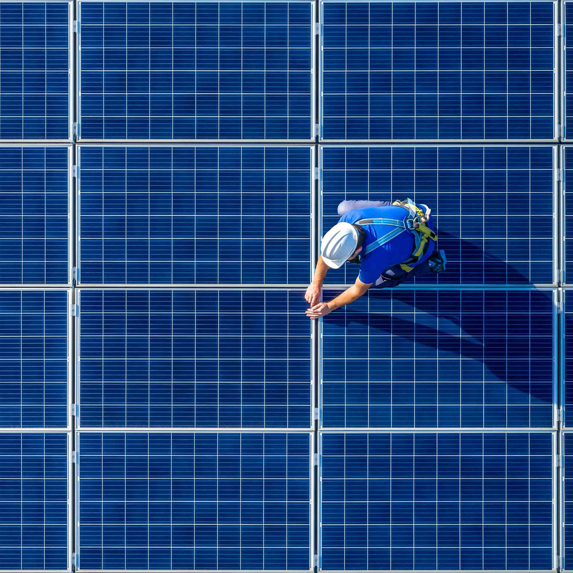 Two men lift solar panels onto a roof.