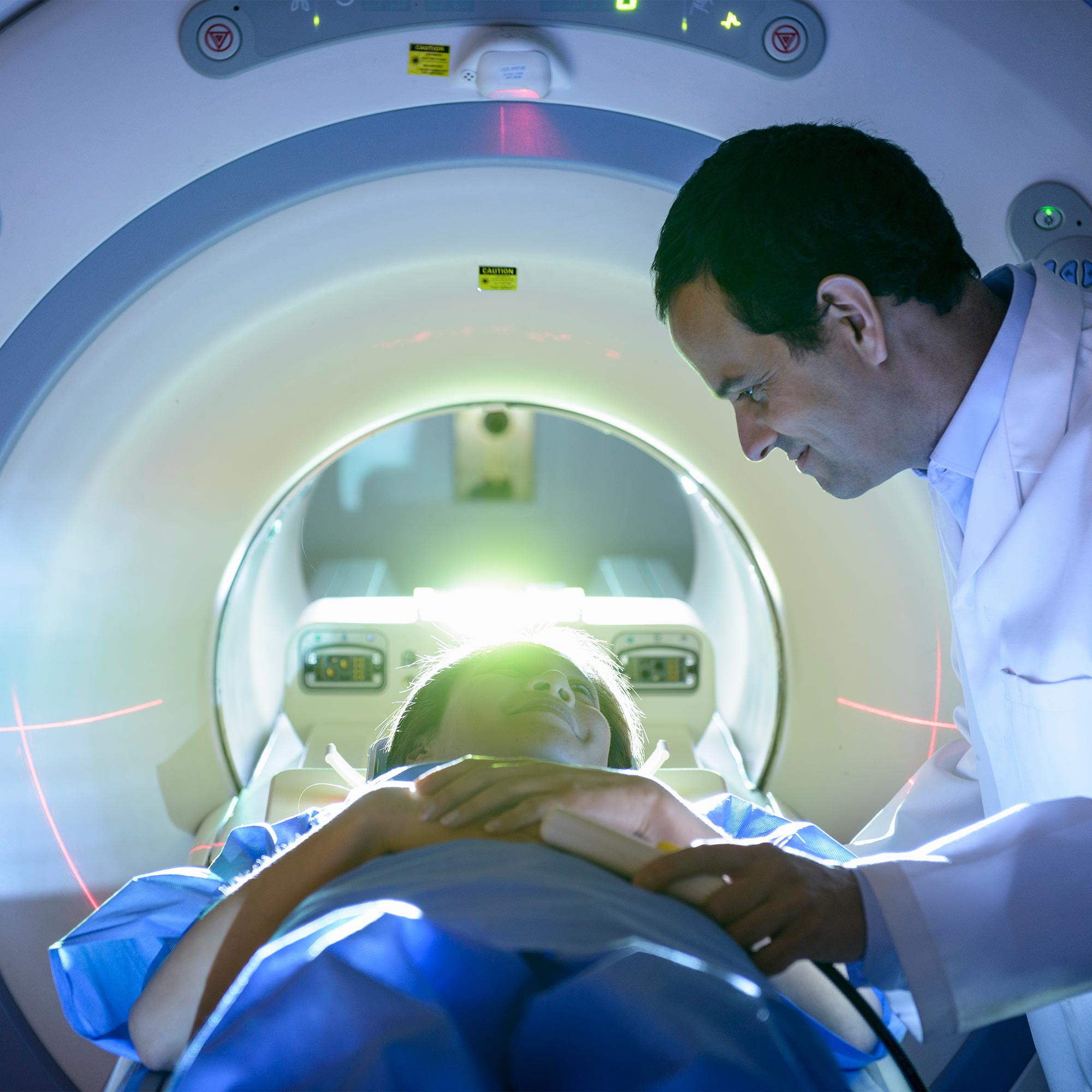A doctor smiles at a patient is lying in an MRI machine.