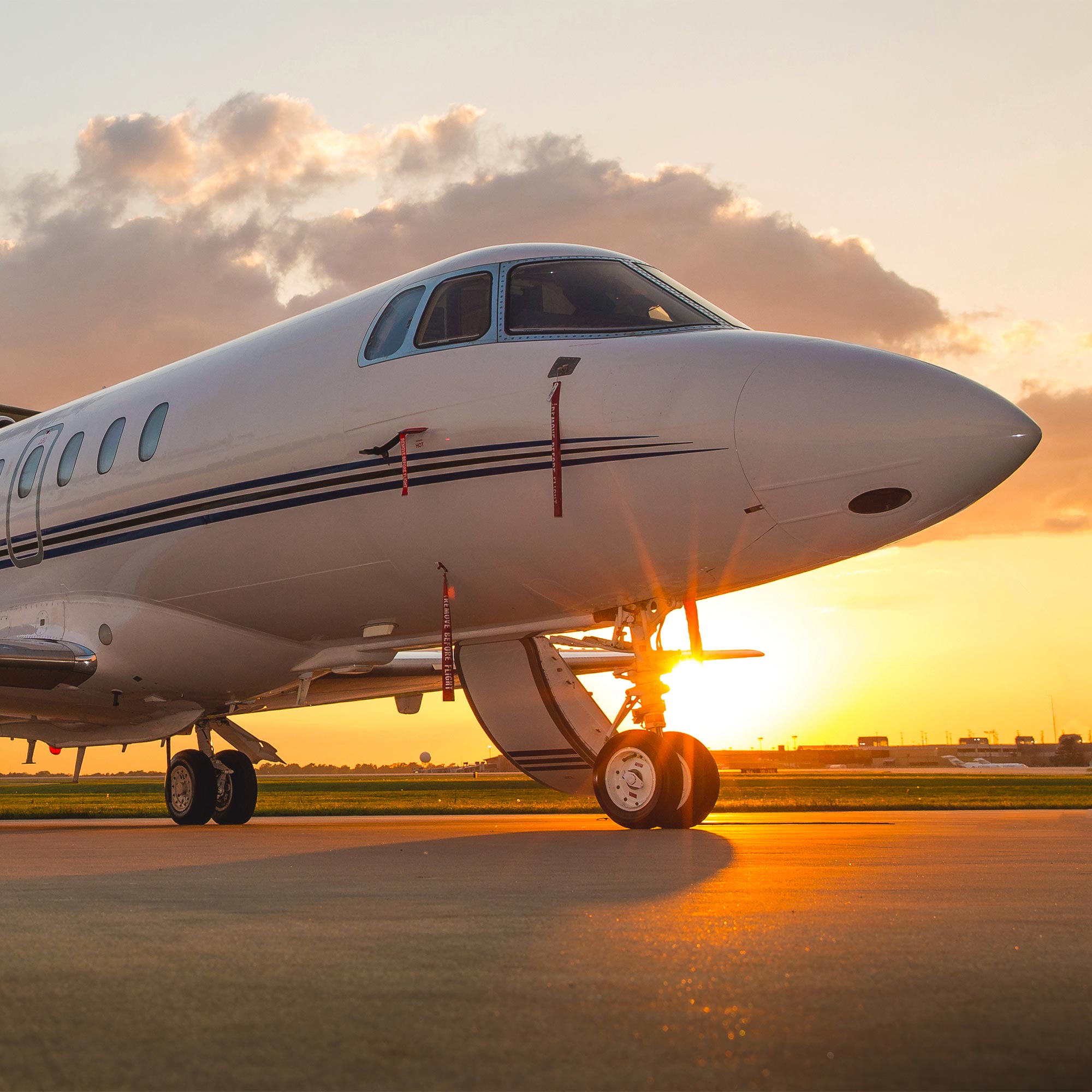 A commercial airplane sits on a runway at sunset.