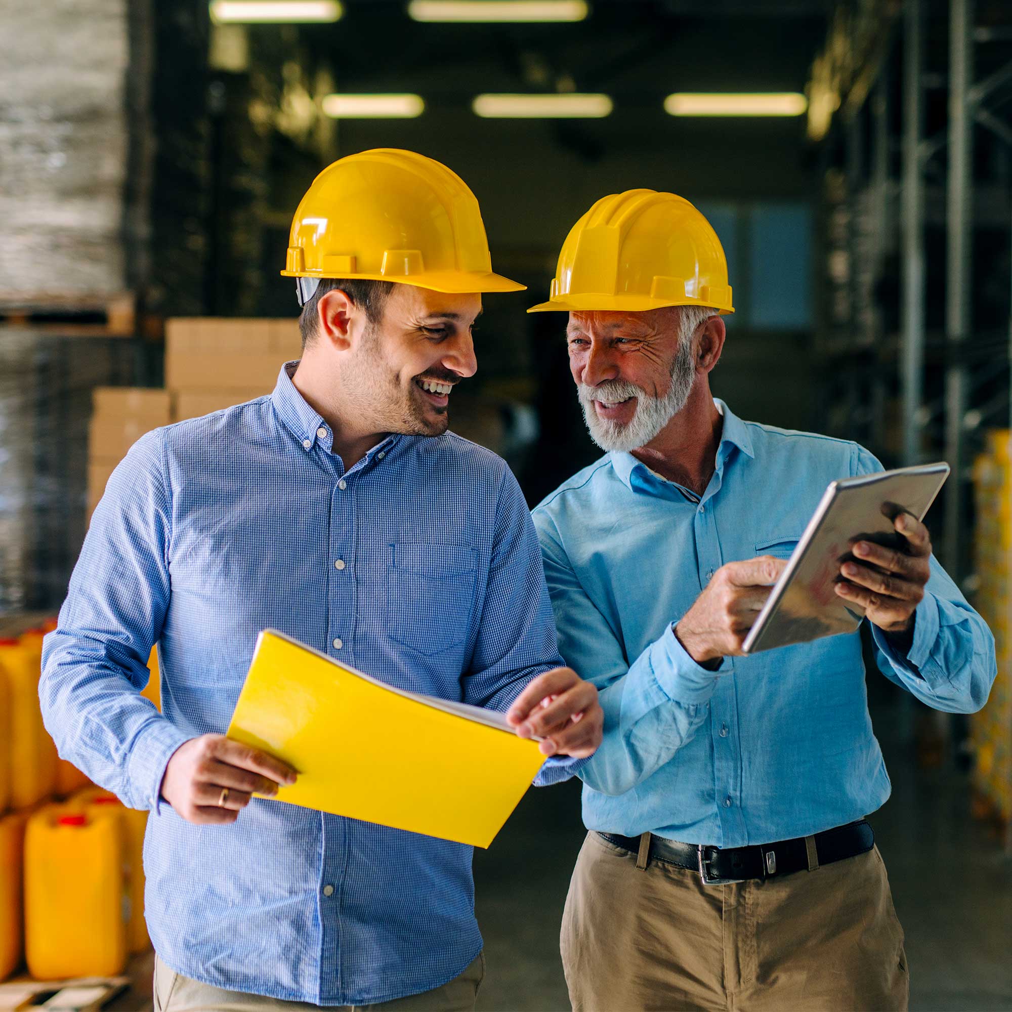 Two men in hard hats smiling and conversing.