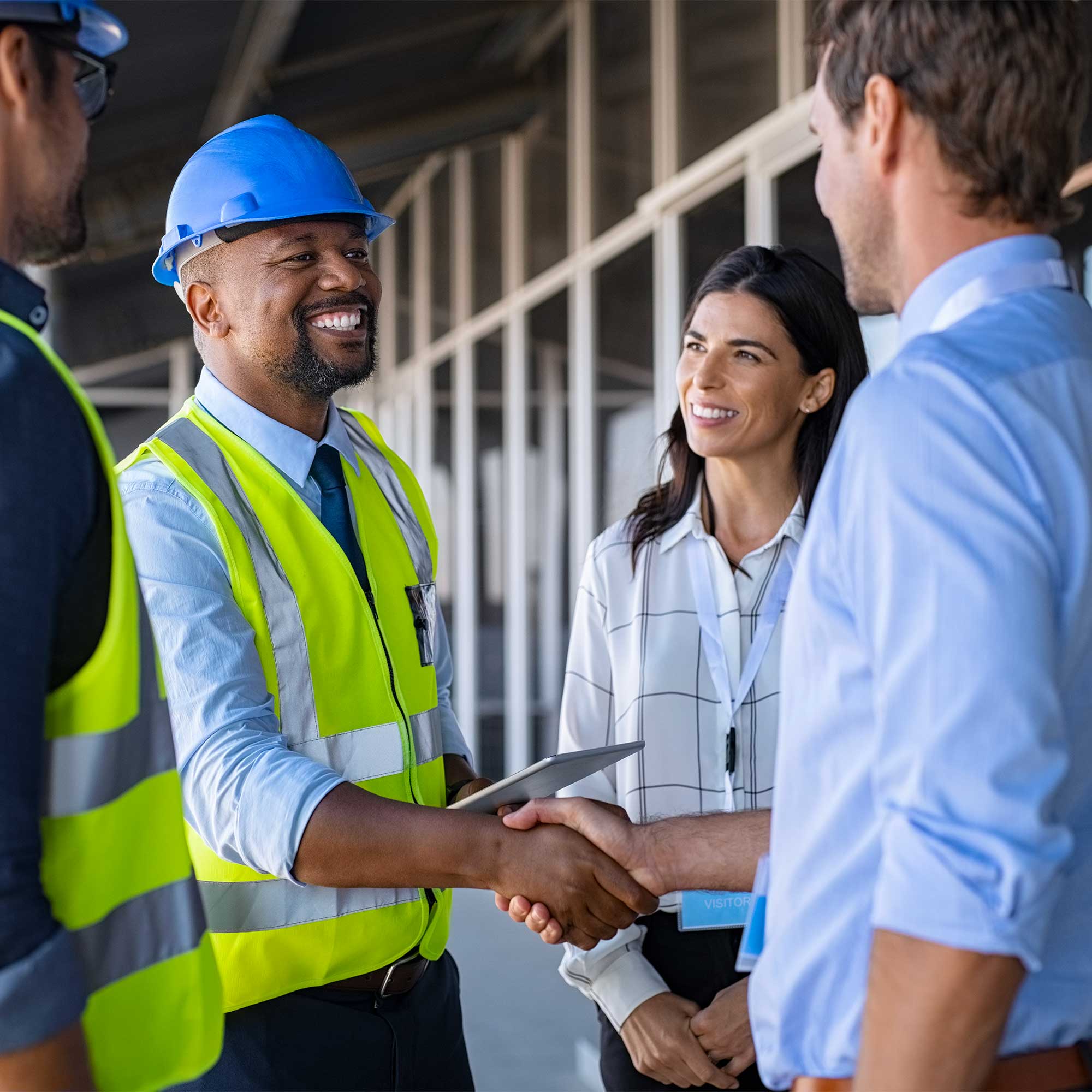 A man in a hard hat shakes hands with people at a construction site.
