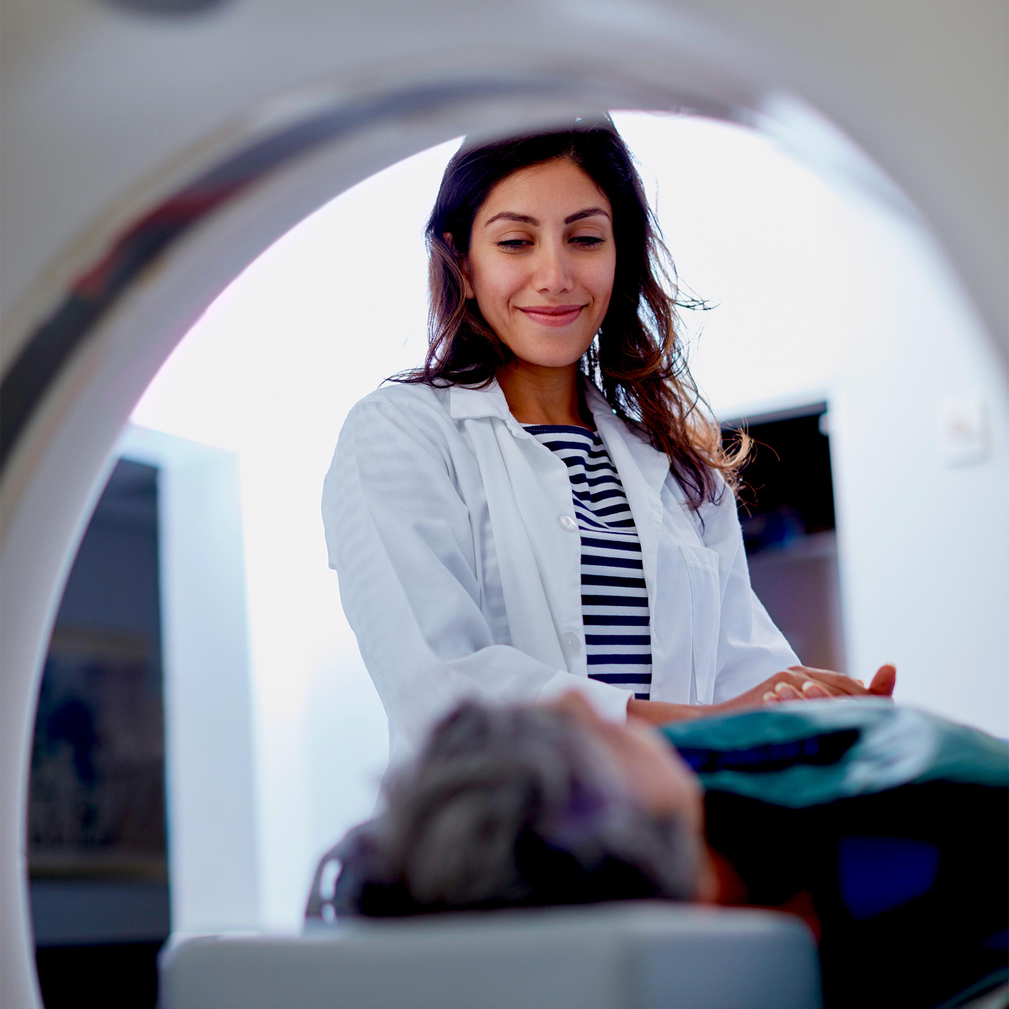 A doctor smiles at a patient is lying in an MRI machine.