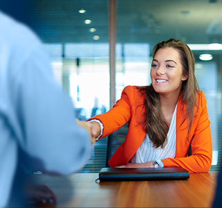 Woman wearing orange business jacket shaking hands with somebody