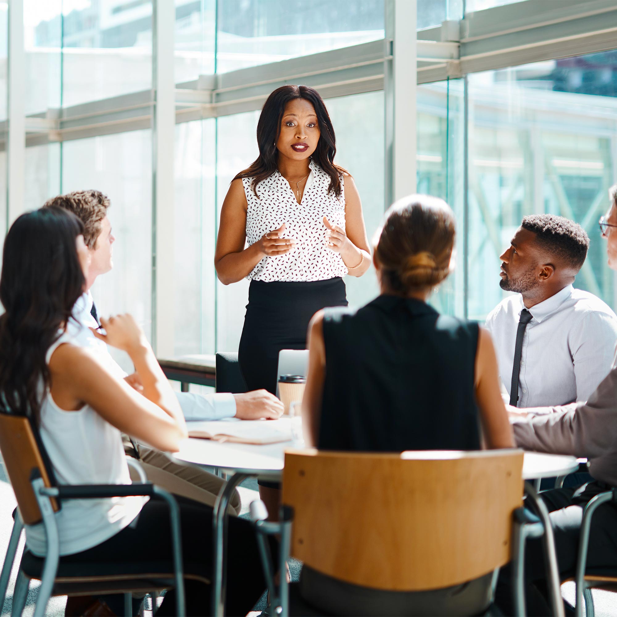 Woman holding a resume talking to another woman at a table with a laptop