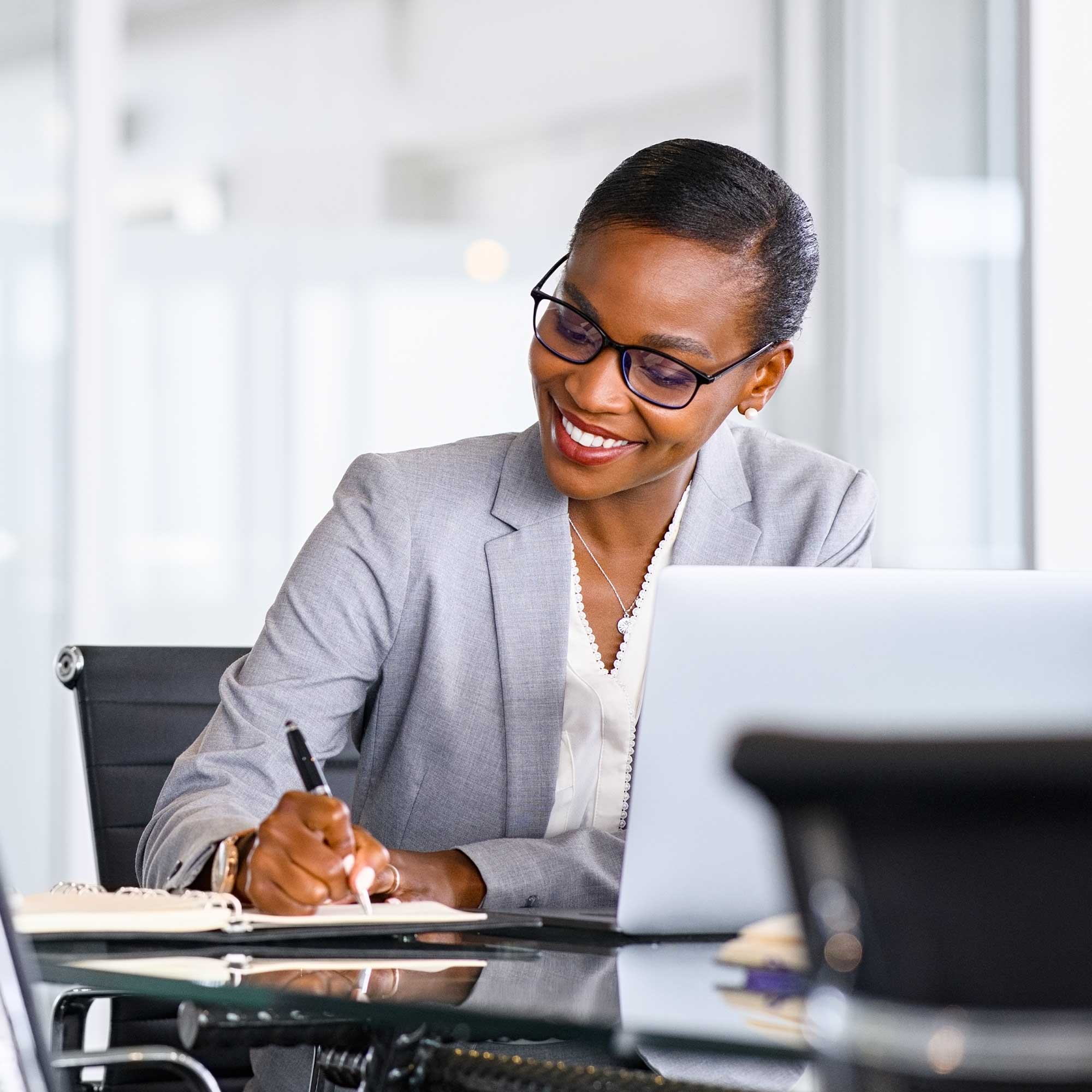 Woman with glasses on top of her head wearing a black jacket pointing at a paper she is holding while talking to a man in a white button up shirt holding a brown bag
