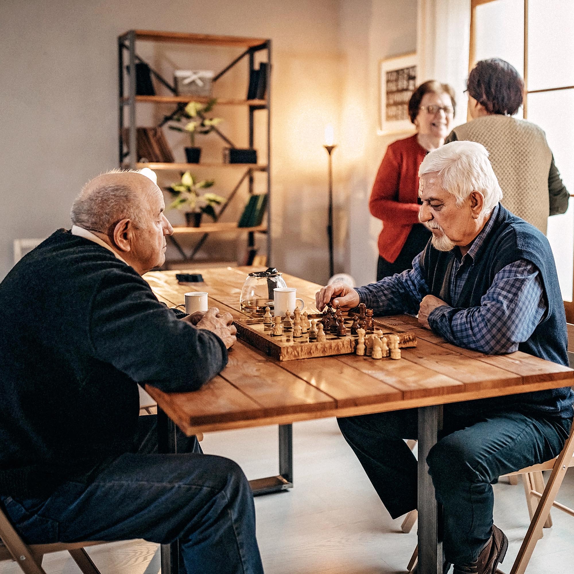 Two elderly men sitting at a table playing chess