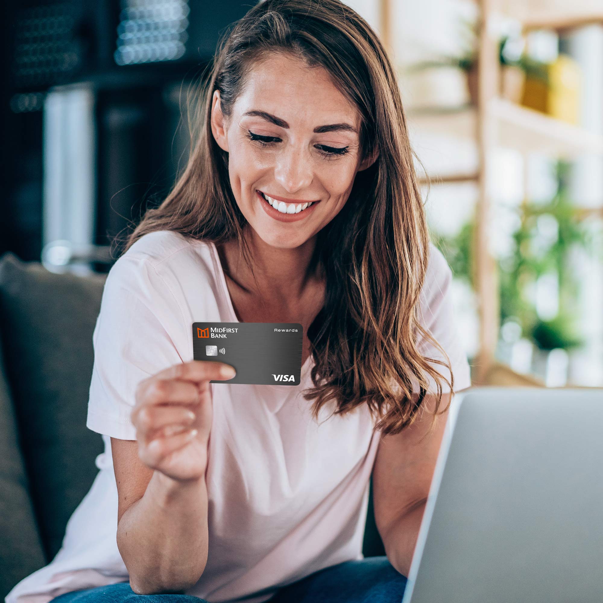 A woman sitting on a couch using a MidFirst Bank debit card