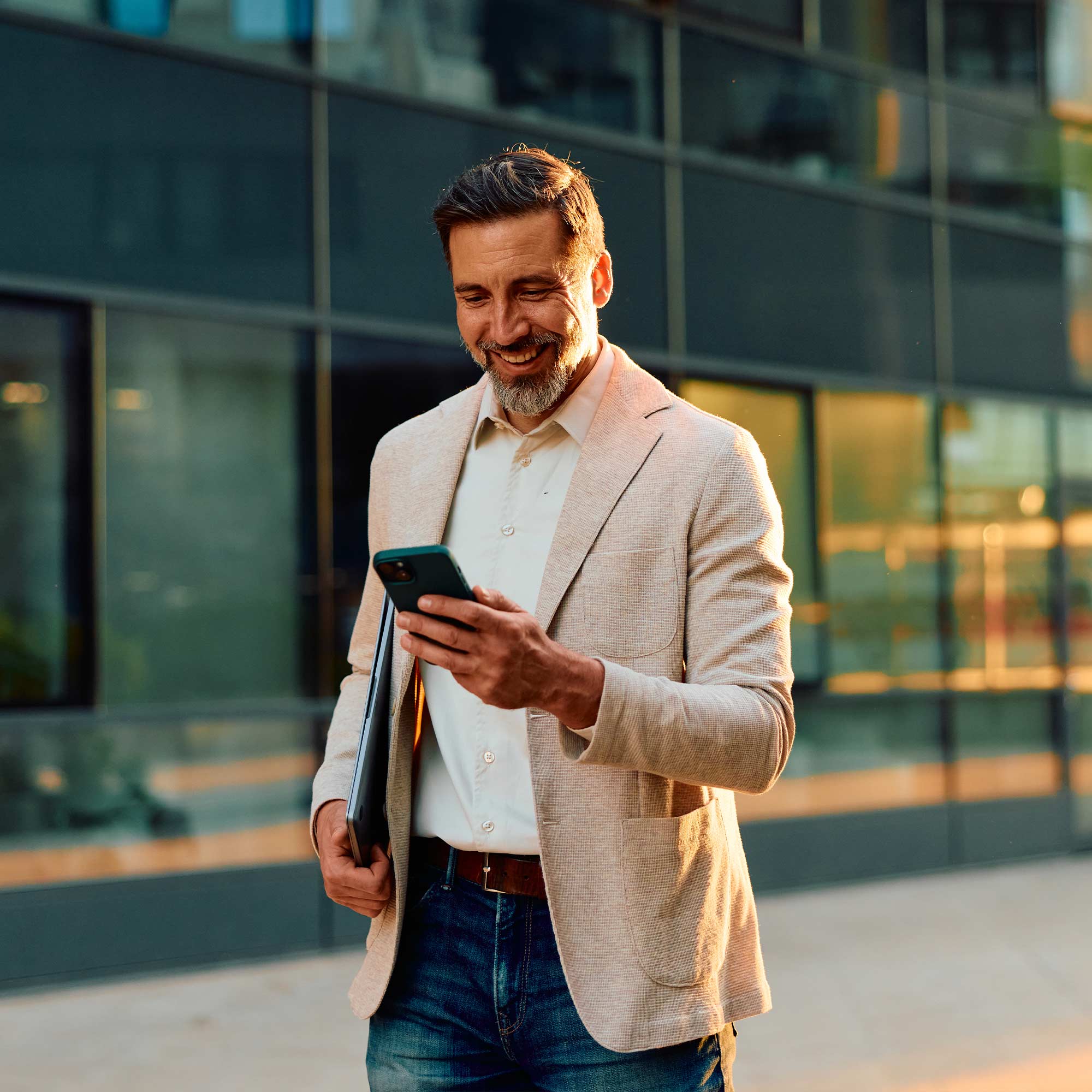 A professionally dressed man talks on the phone and smiles.