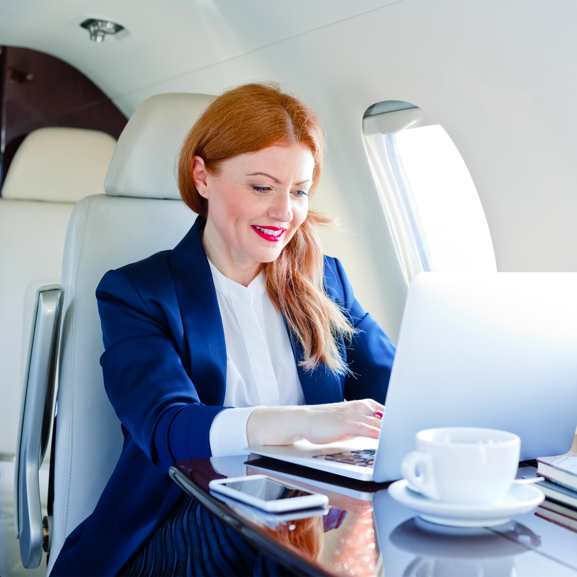A woman types on her computer as she sits on an airplane.