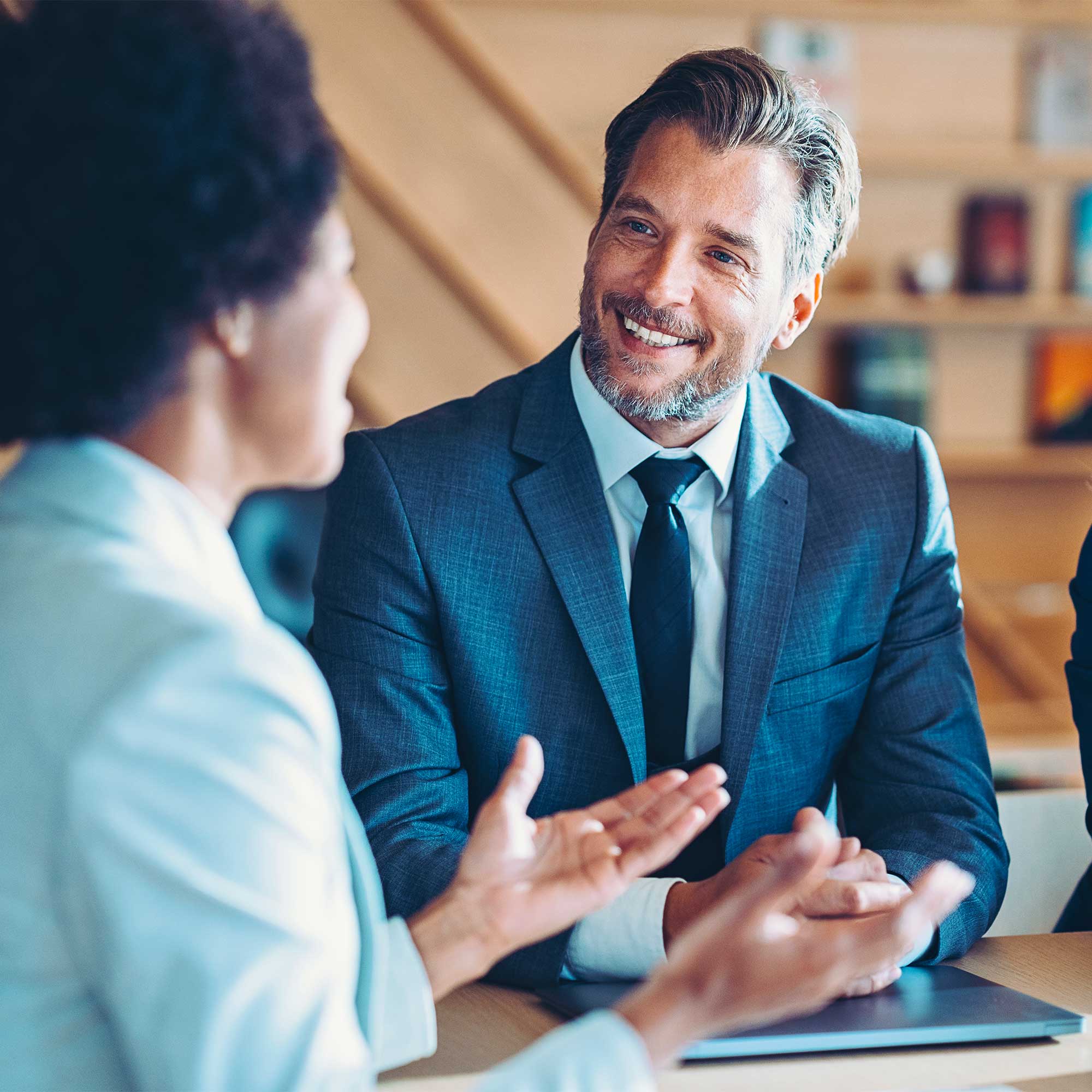 A professionally dressed man talks to a woman at a table.
