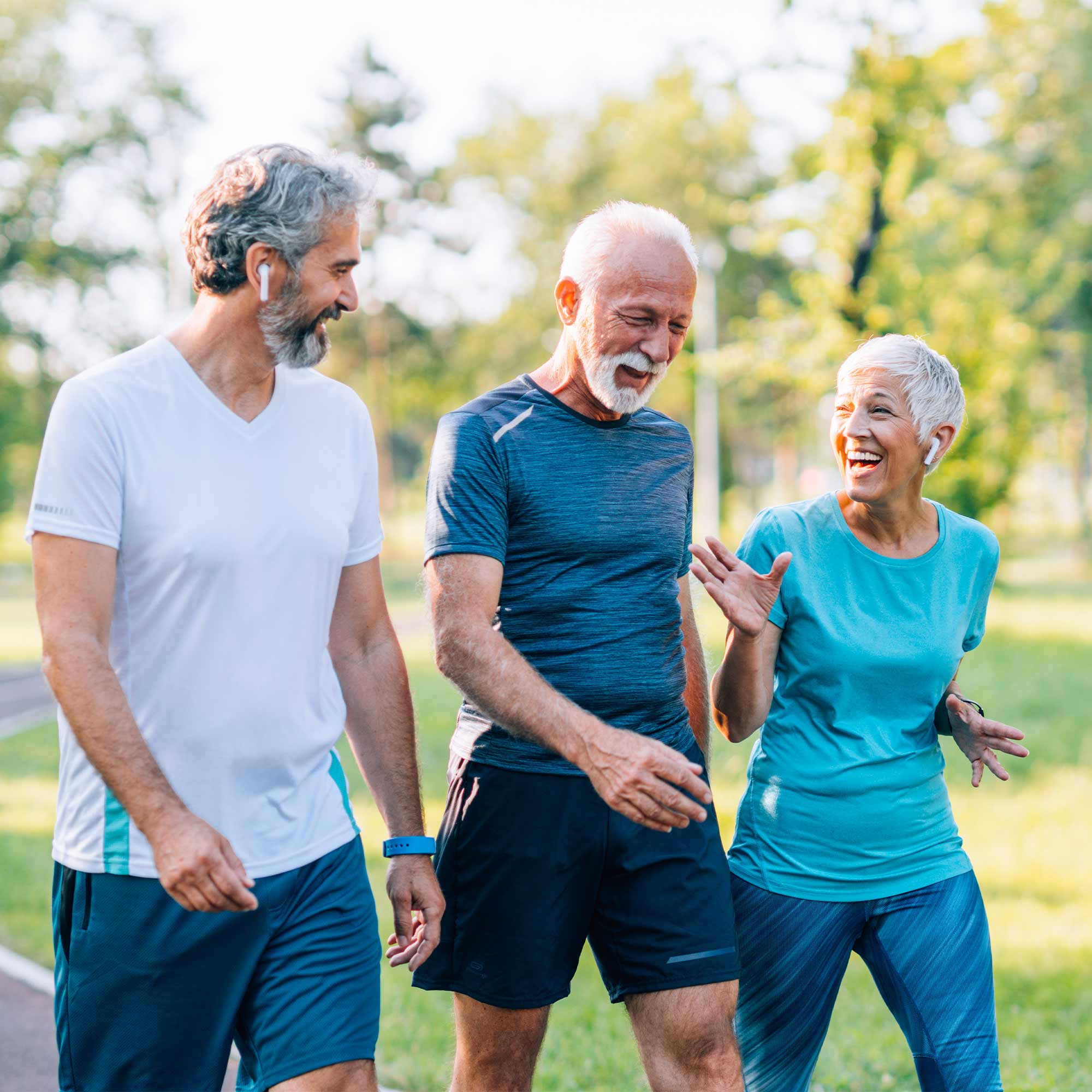 Two men and a woman are talking and walking the trail at the park.