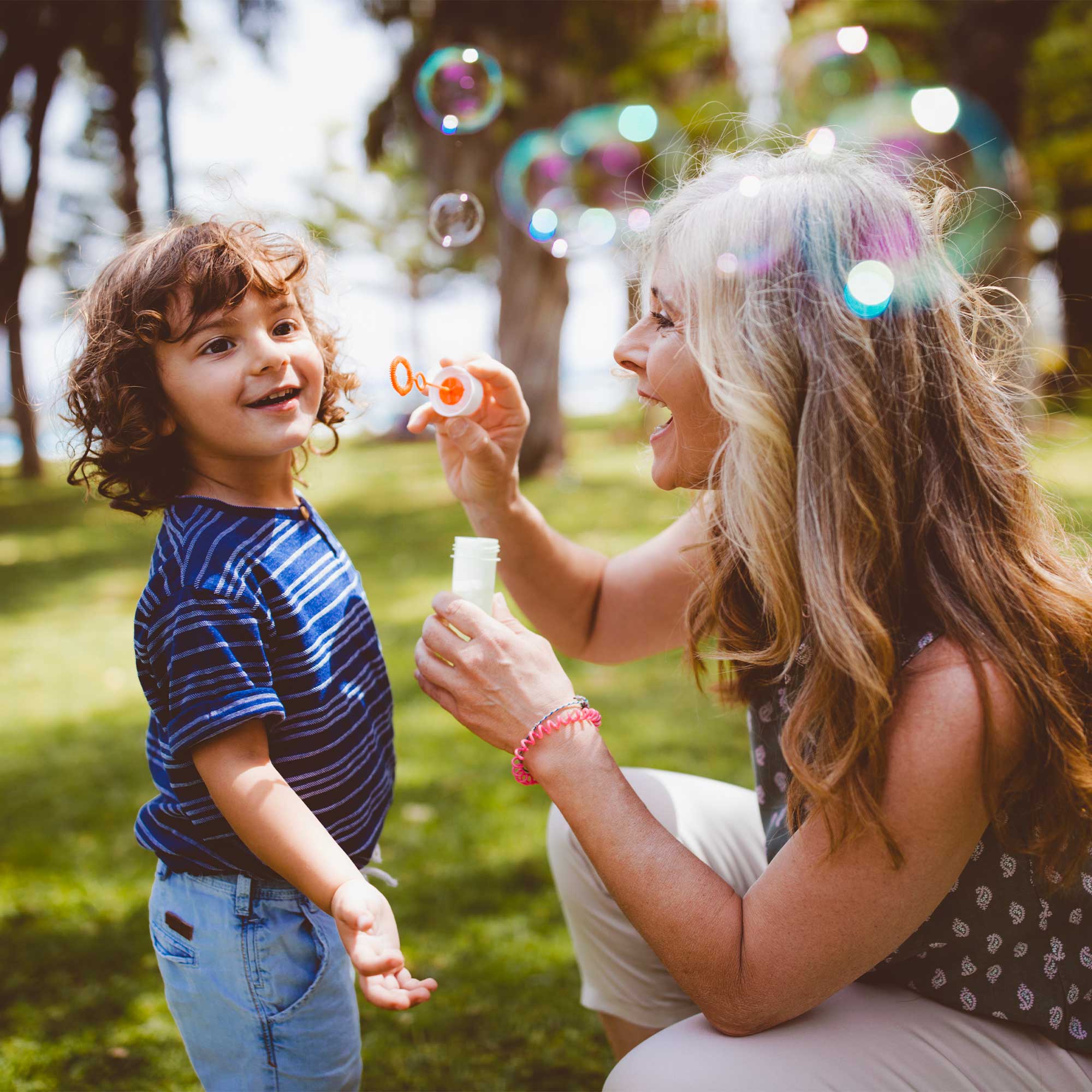 A man and woman sit on a couch smiling as they use the laptop.