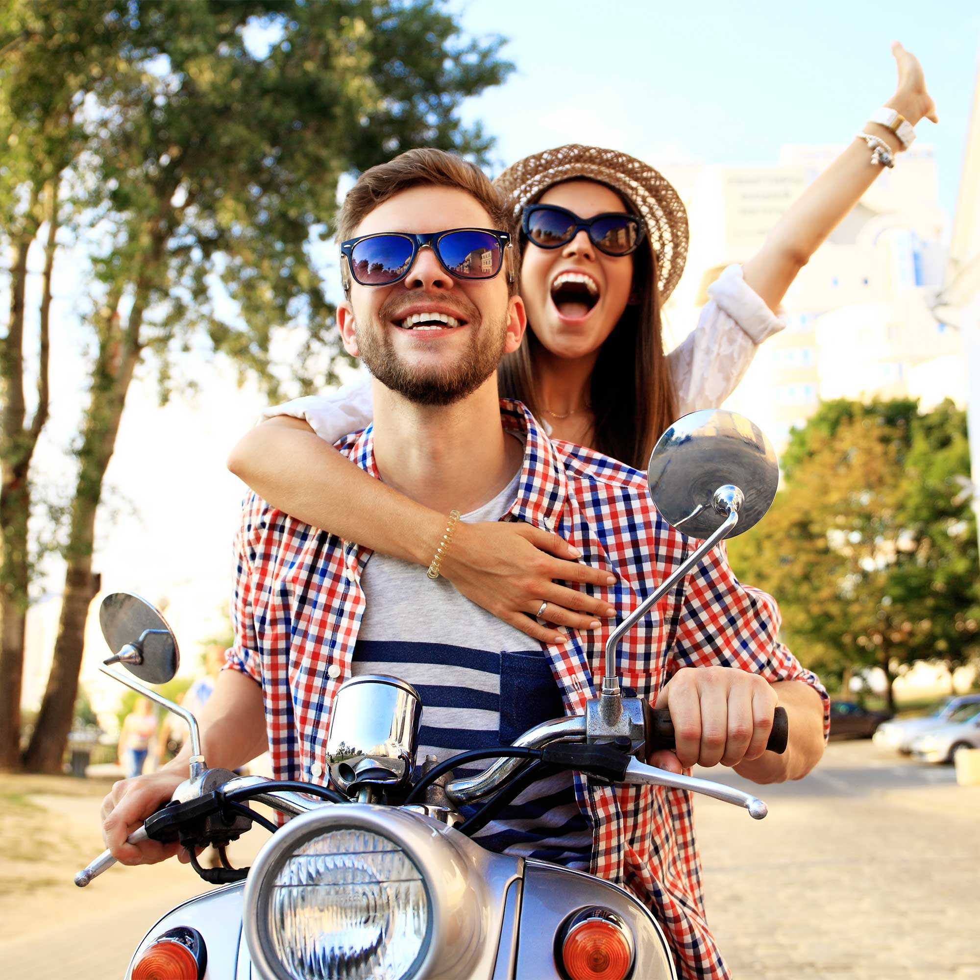 A man and a woman wearing sunglasses riding a motorcycle.