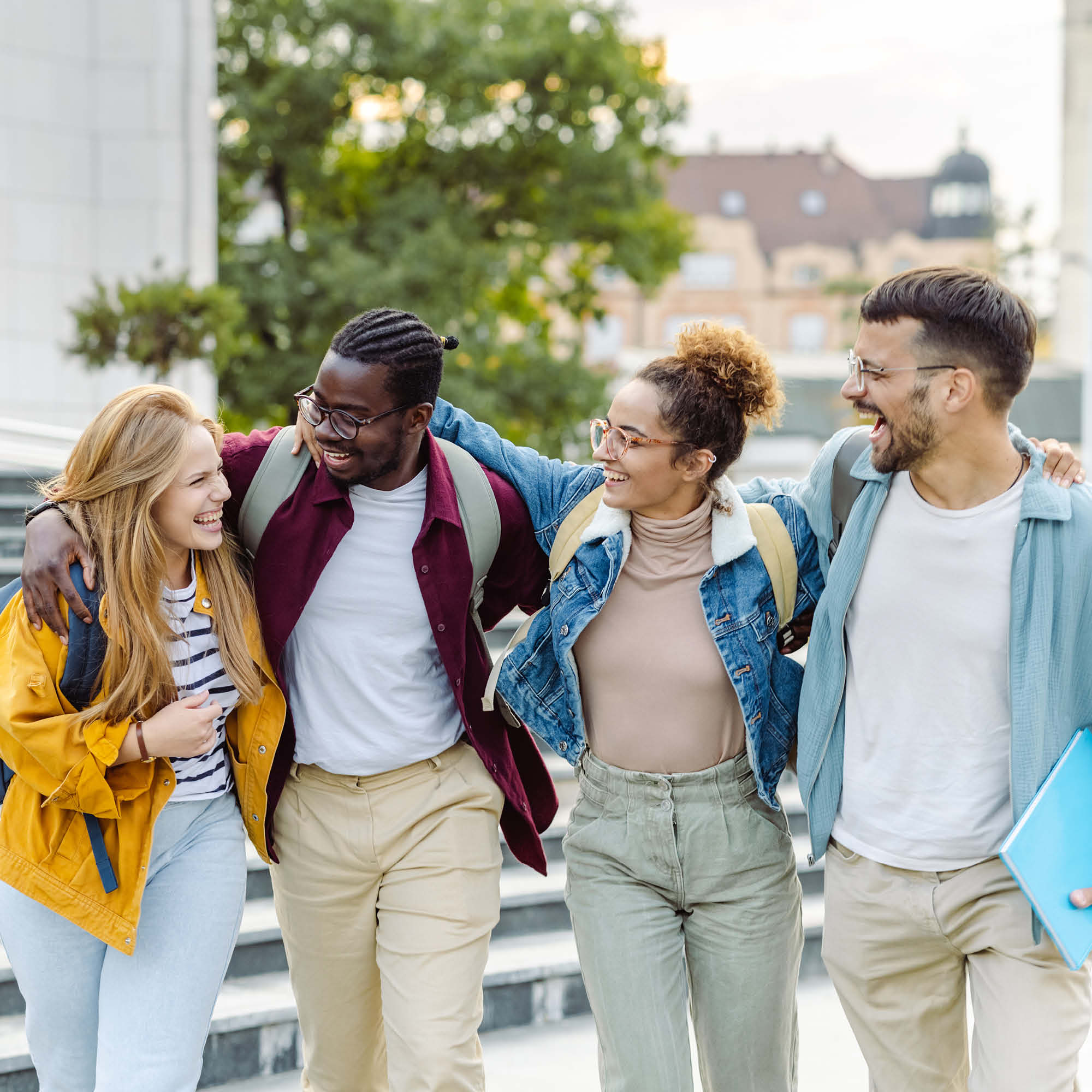 Four students with arms around each other walking and smiling.