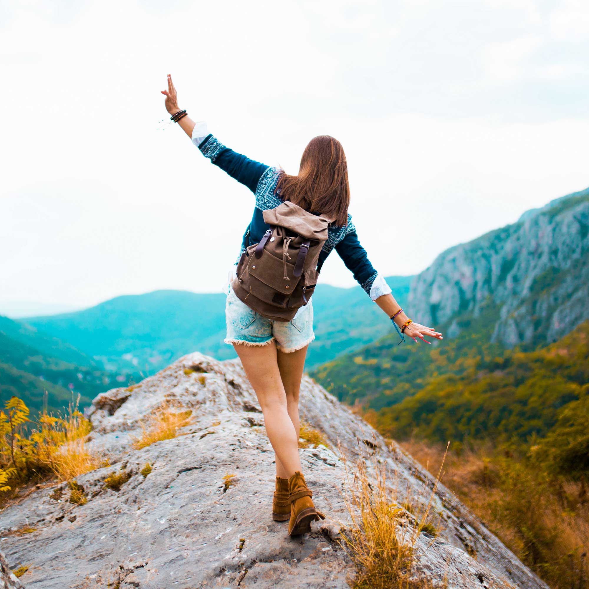 Woman walking and balancing herself as she walks along a ledge.