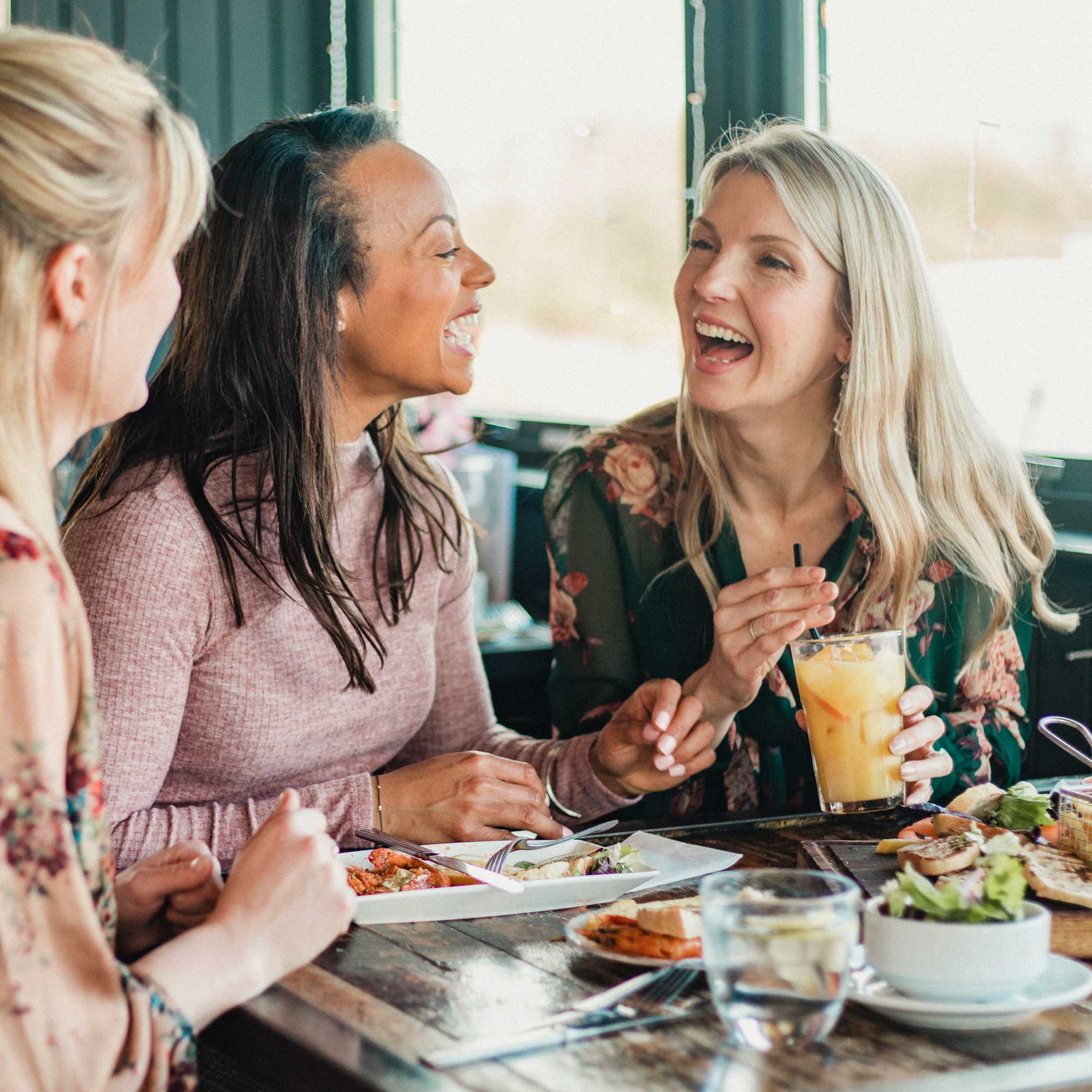 Women laughing over brunch.