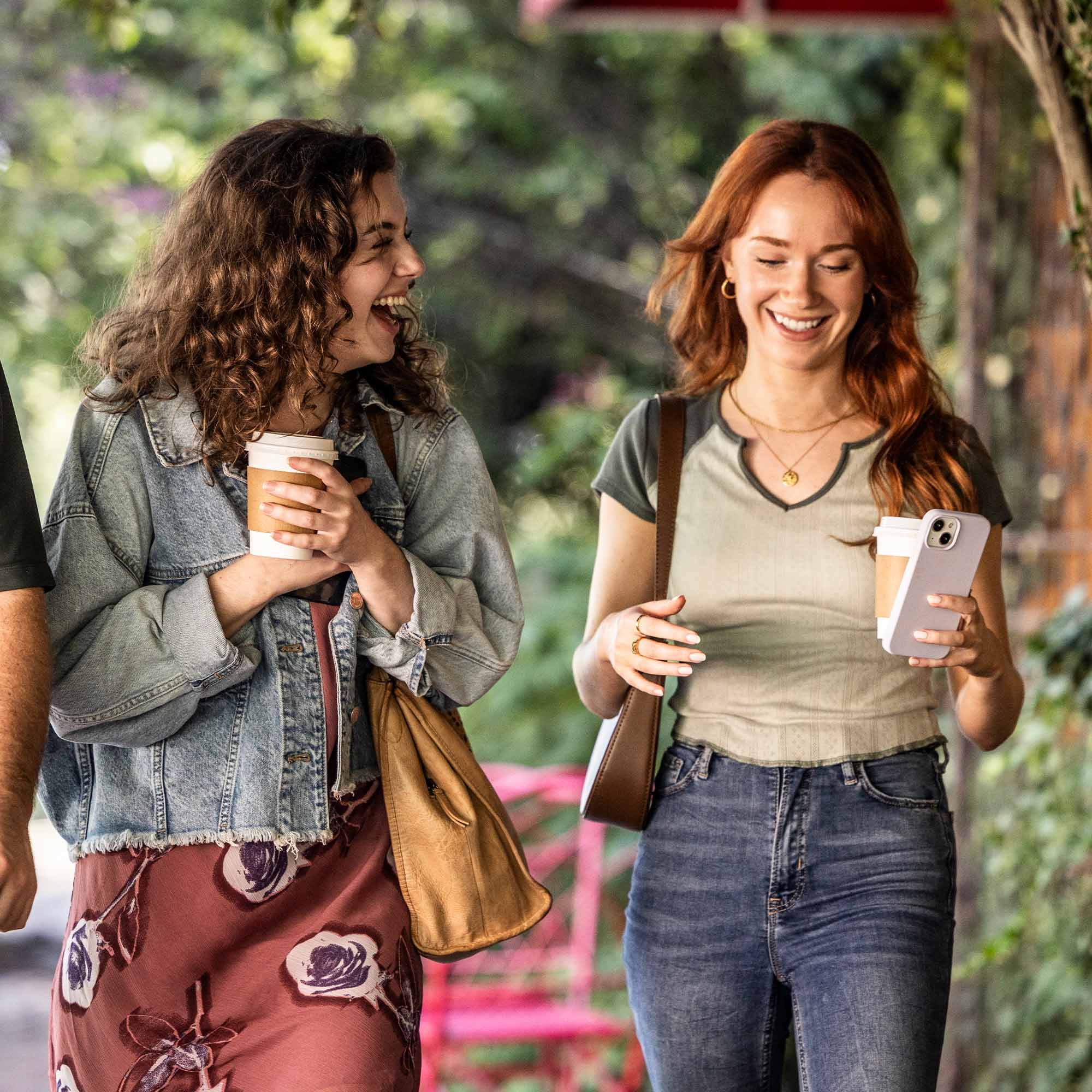 Three friends sitting together while drinking coffee and smiling.