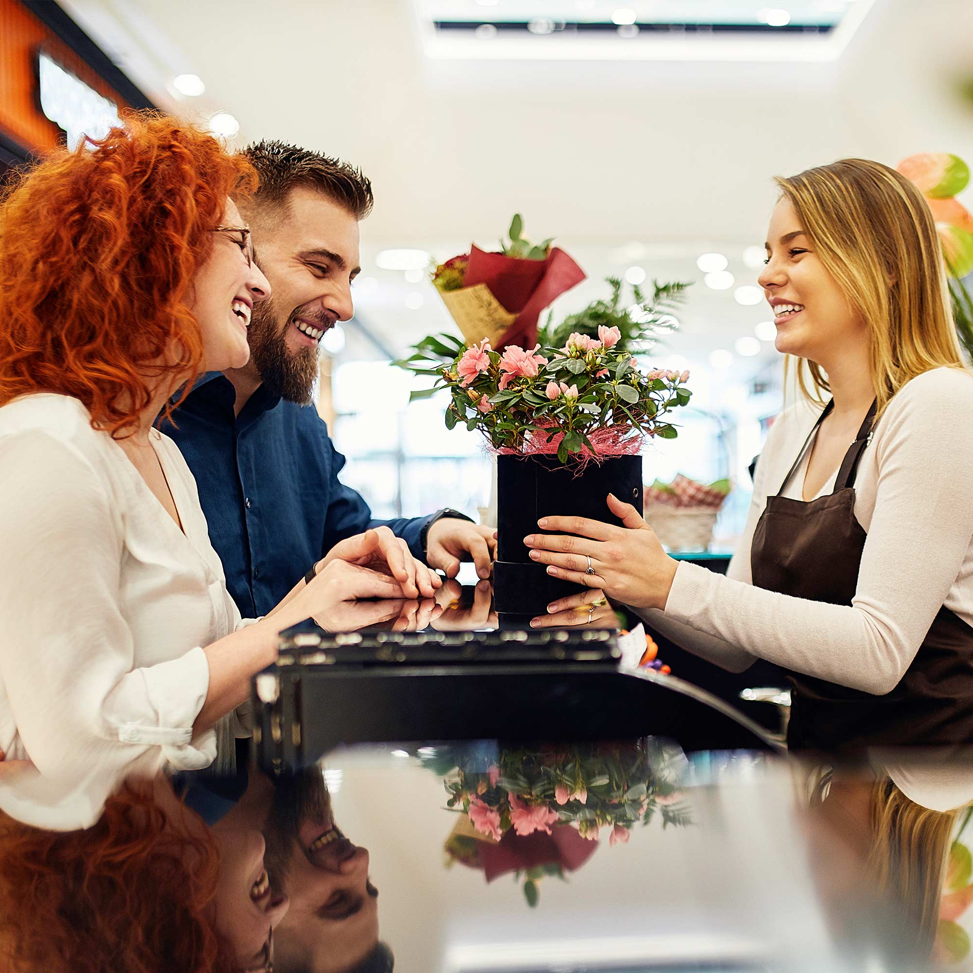 Professionally dressed man working on a laptop, smiling and looking at his credit card.