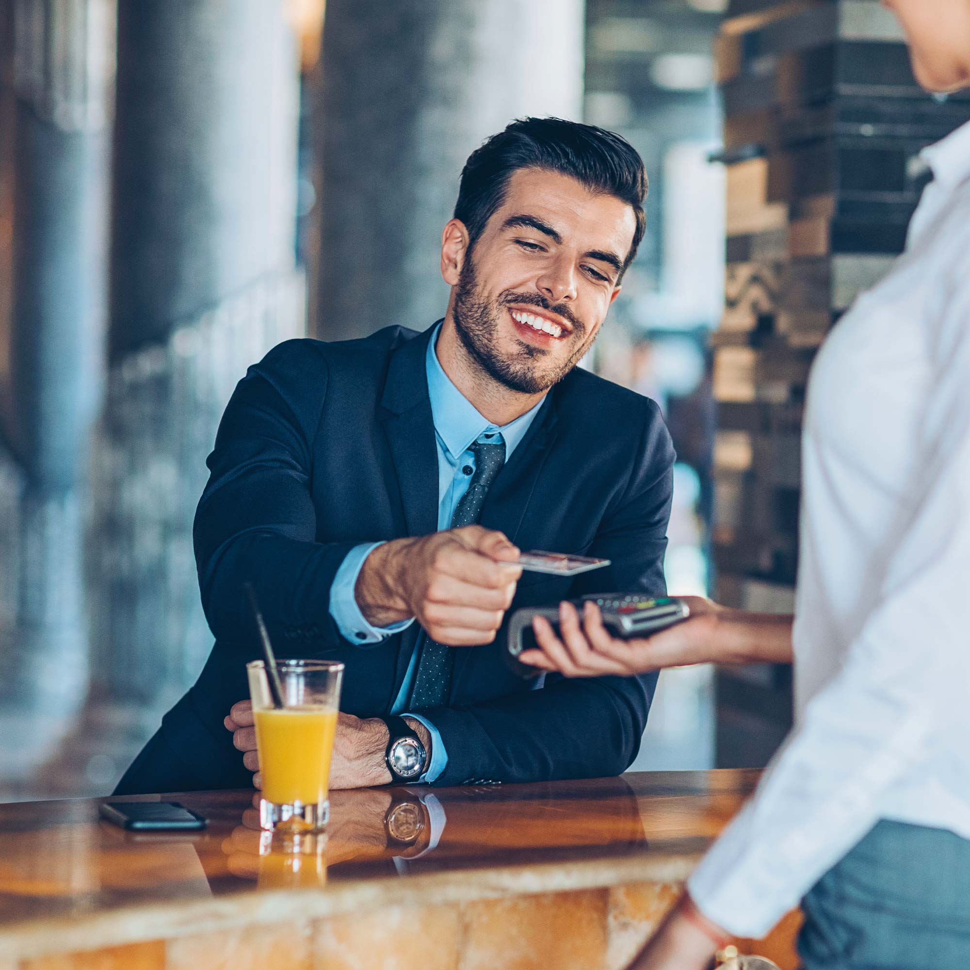 Man sitting at a bar and using a credit card to make the transaction.