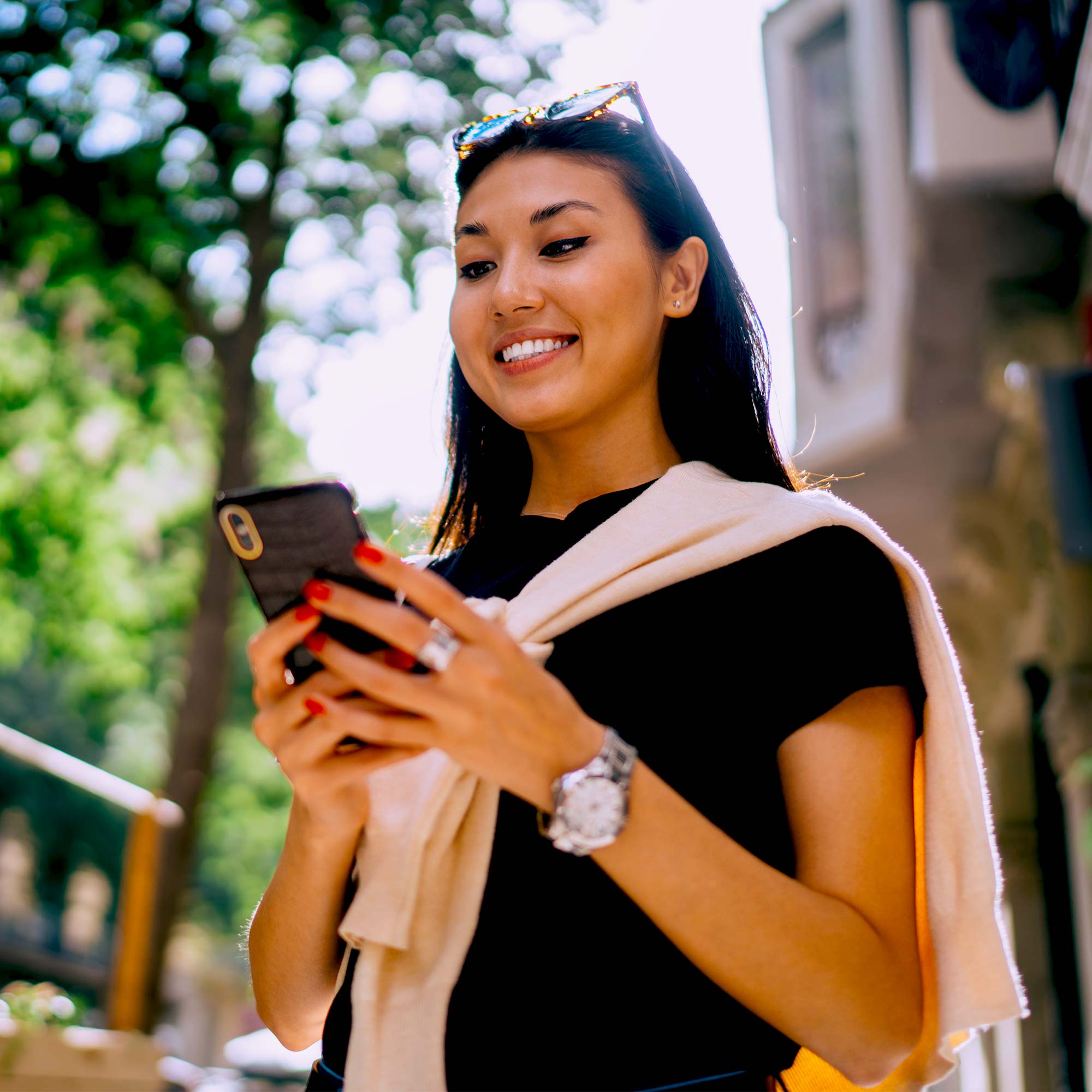 A woman smiling and looking down at her phone.