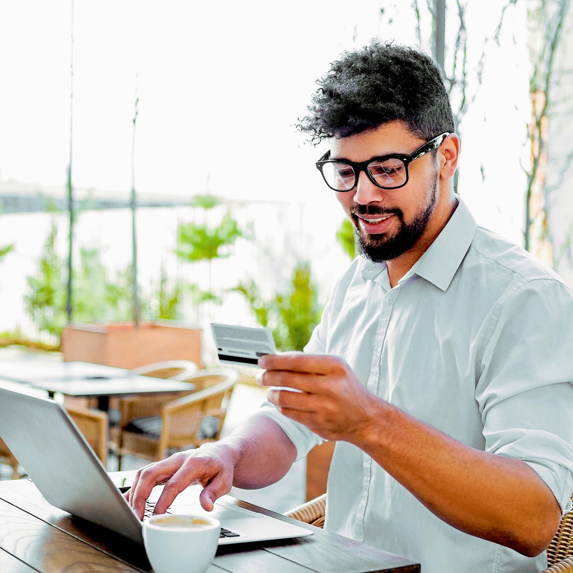 Professionally dressed man working on a laptop, smiling and looking at his credit card.