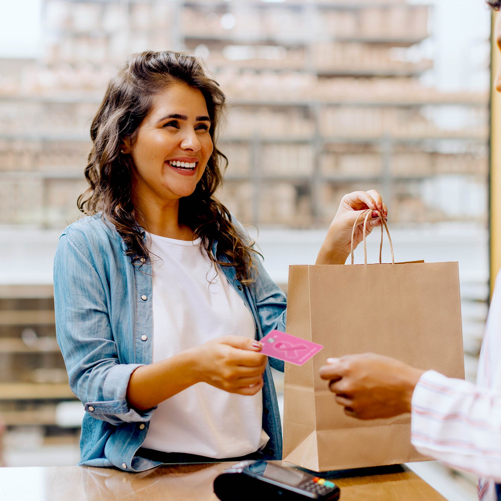Woman using a MidFirst Bank Pink Card to make a purchase.