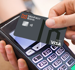 Closeup of a man's hand using a MidFirst Bank debit card to pay via contactless.