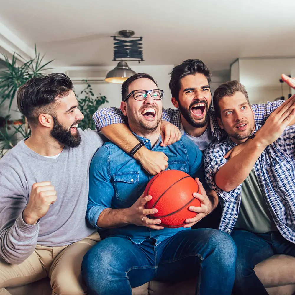 Group of guys sitting on the couch cheering and yelling at the tv.