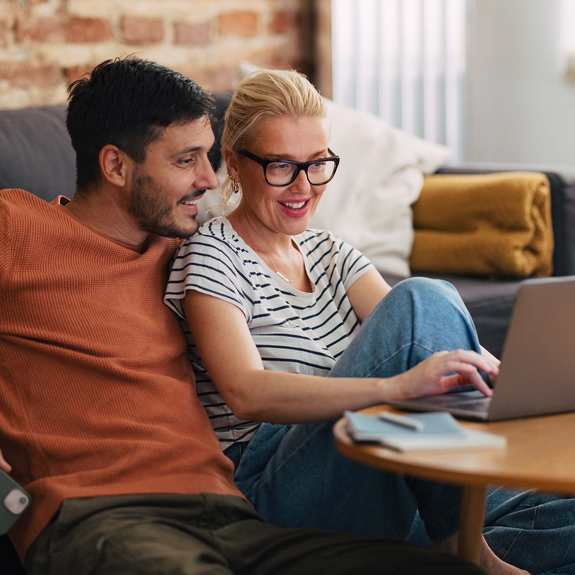 A woman peers over her husbands shoulder as she points to the screen of the computer.