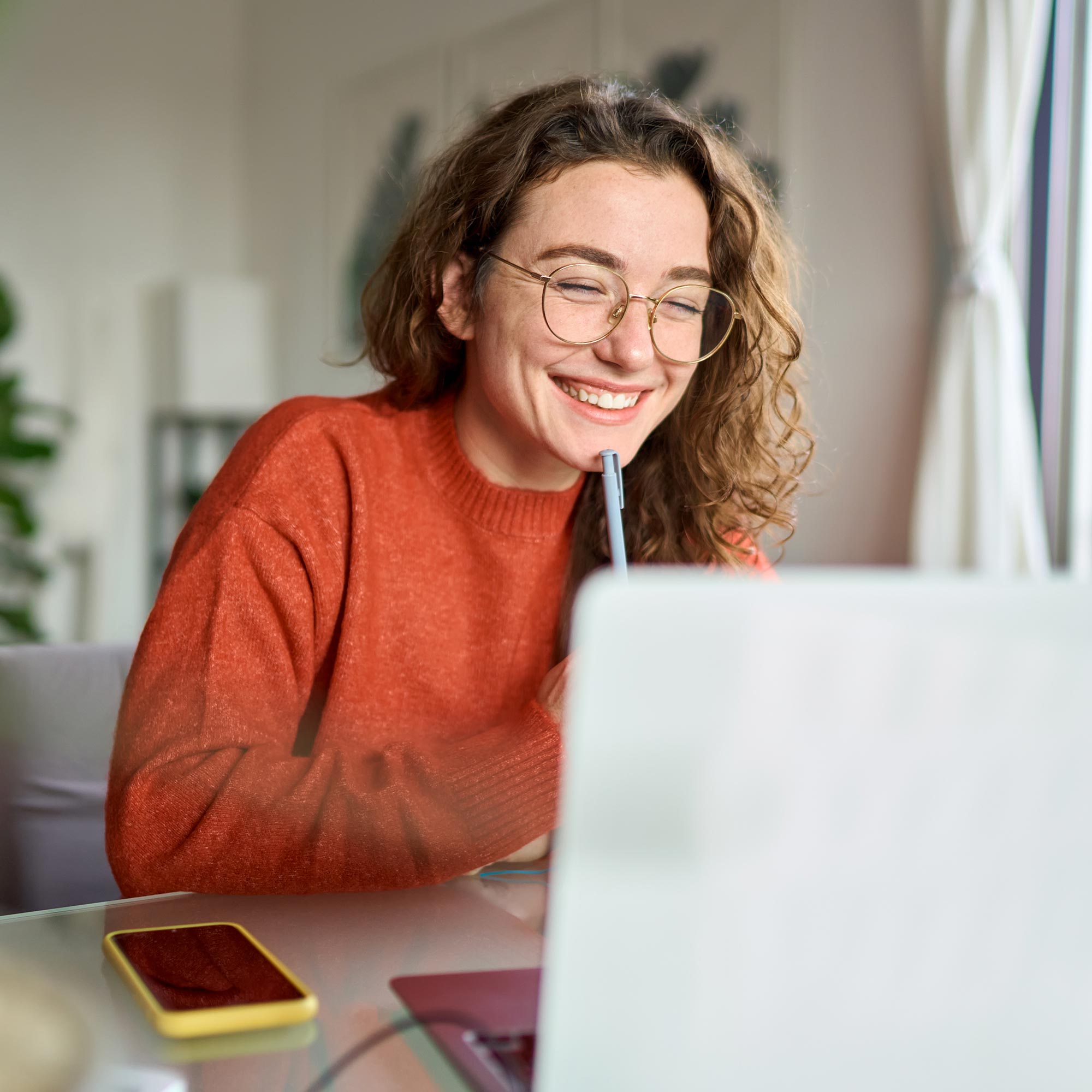 A woman sits at her home while working on her macbook.