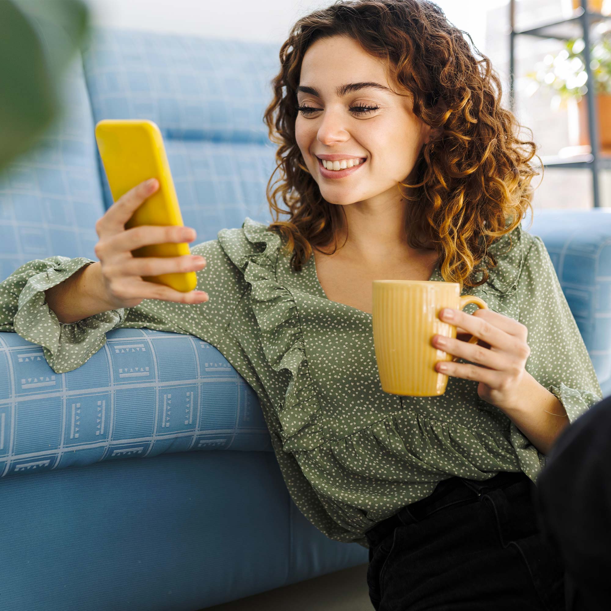 A woman holding her phone in one hand and a coffee cup in the other