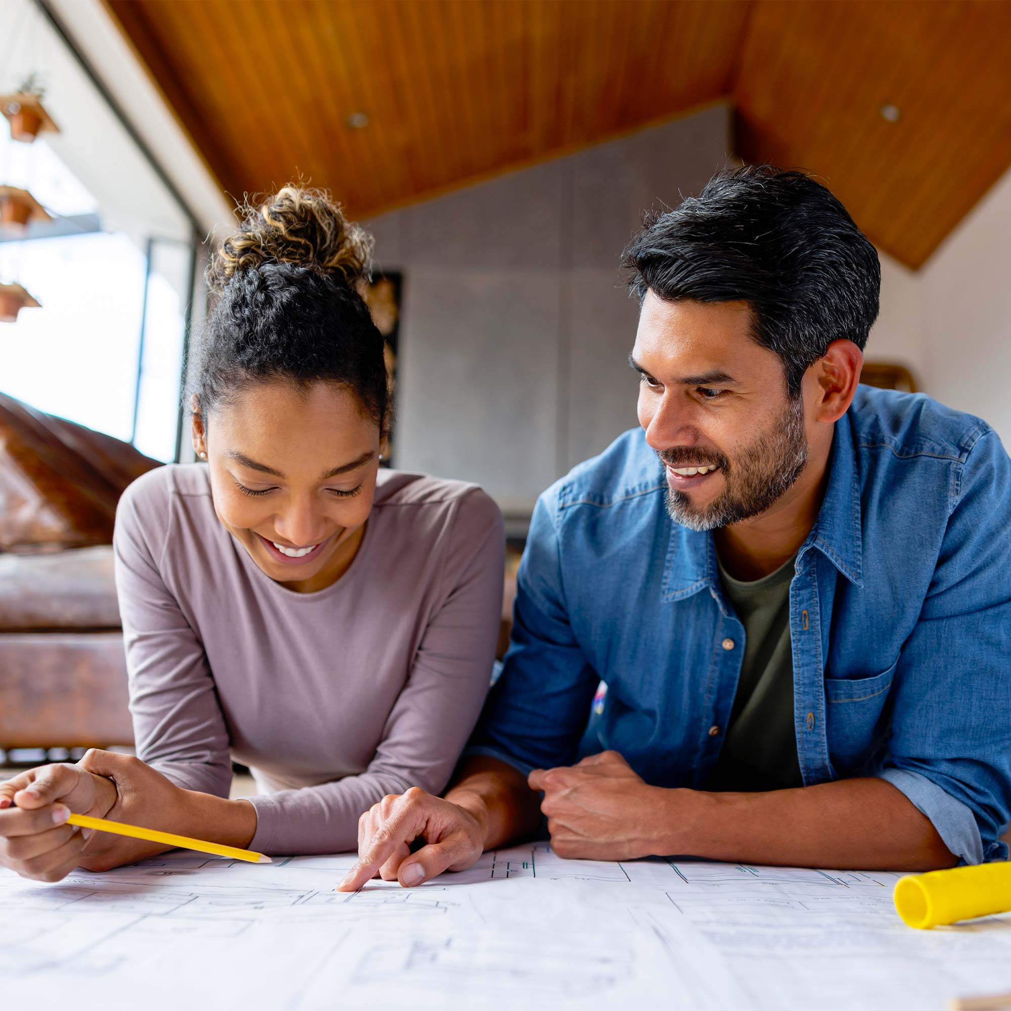 A man and woman smile as they review a blueprint of their house.
