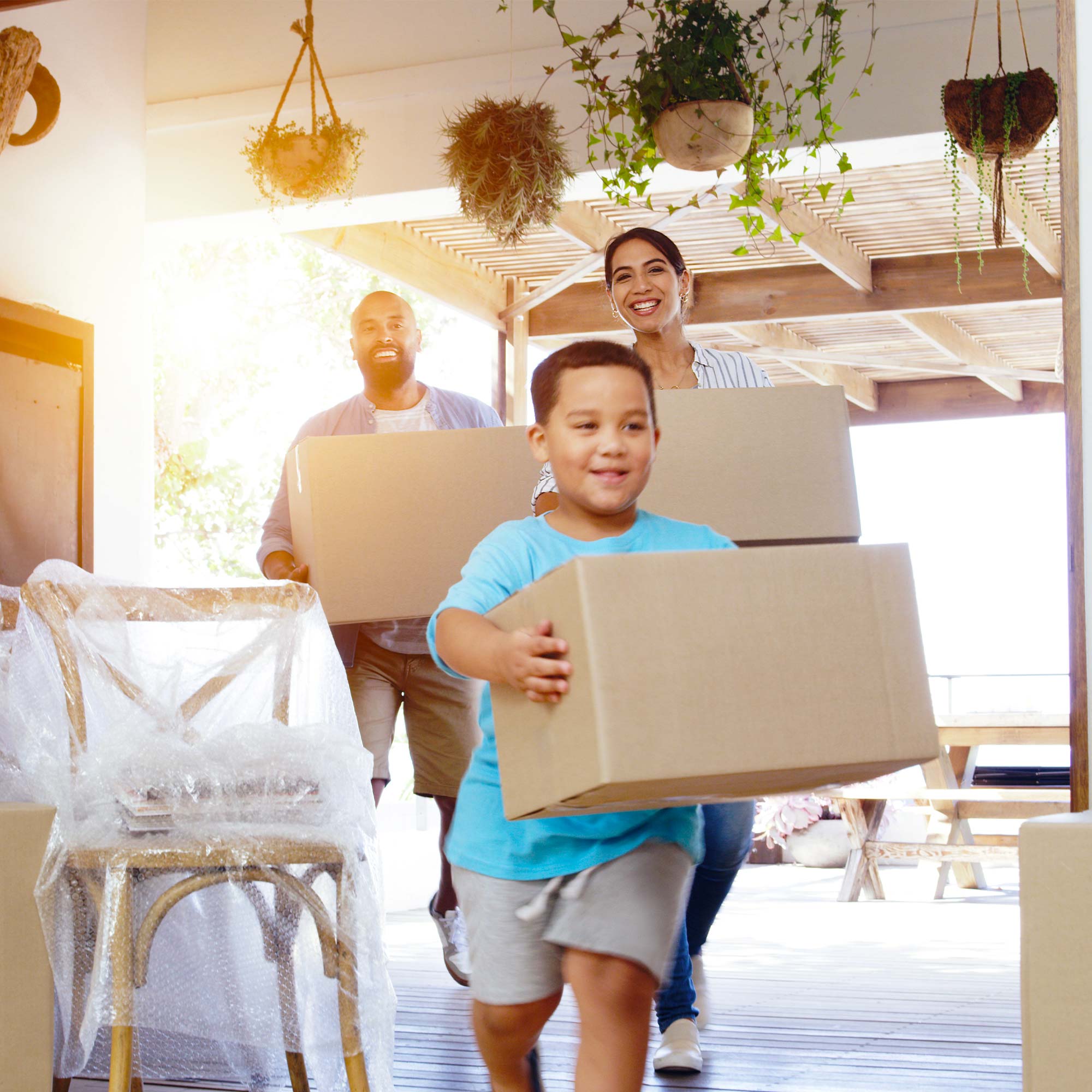 A family of three carrying boxes into their new home.