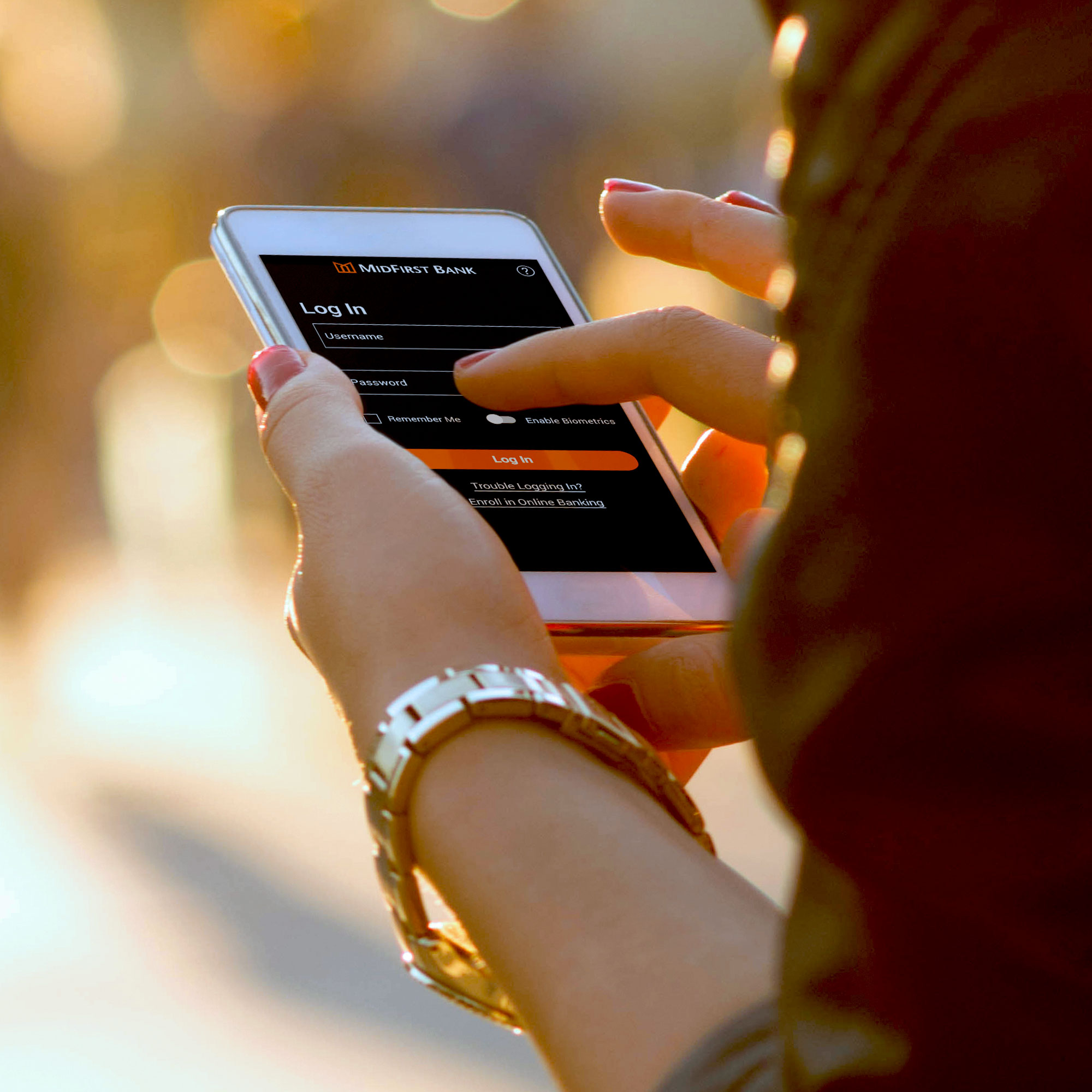 A woman uses her cell phone to log in to the MidFirst Bank mobile app.