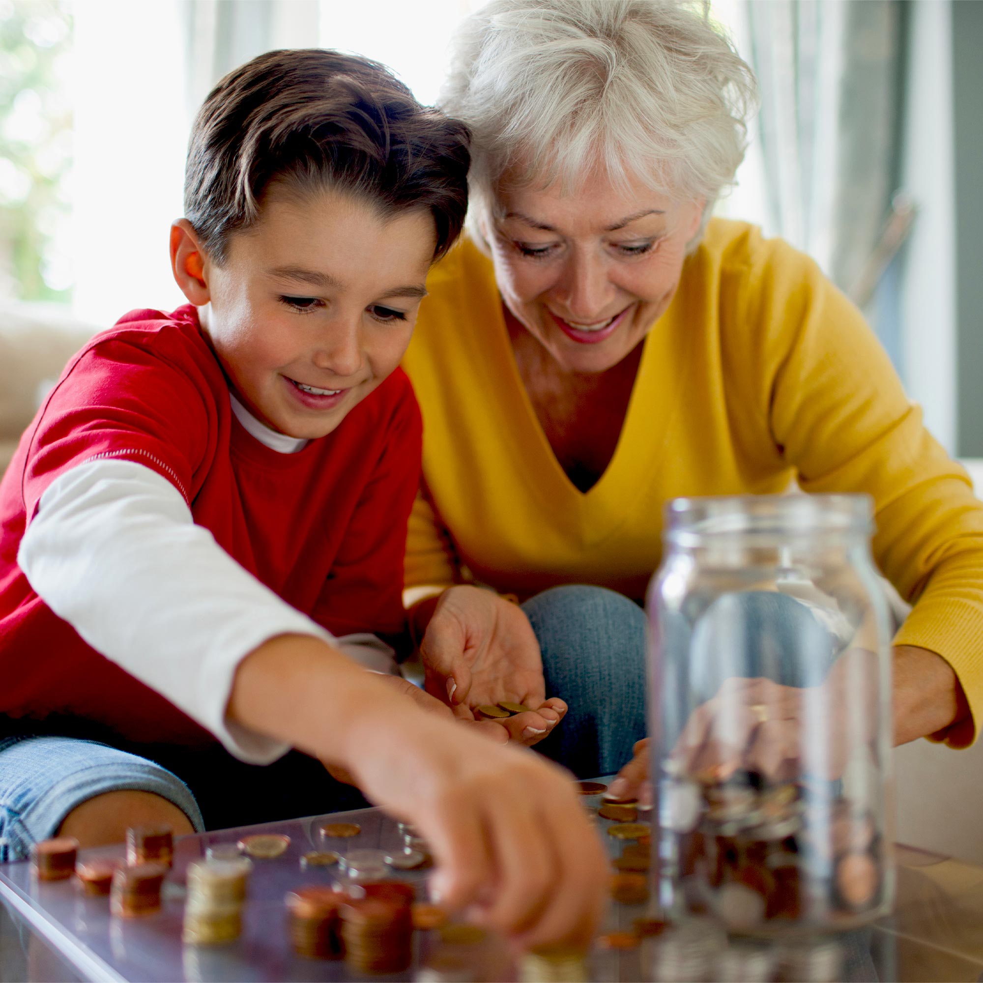 Grandma wearing a yellow shirt helps her grandson count his spare change.